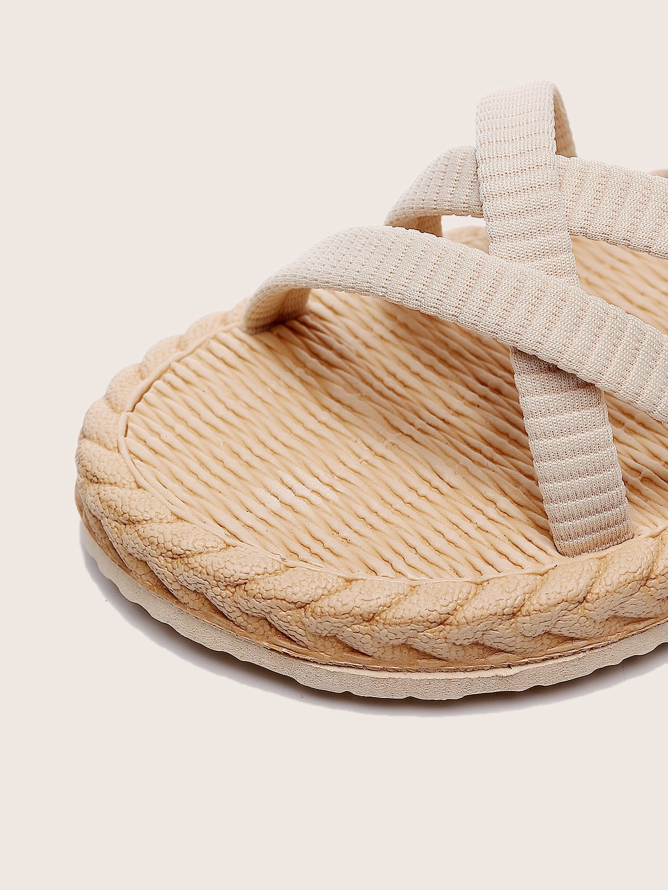 Beige women’s minimalist flat sandals with criss-cross fabric straps, open toe, and slingback design.