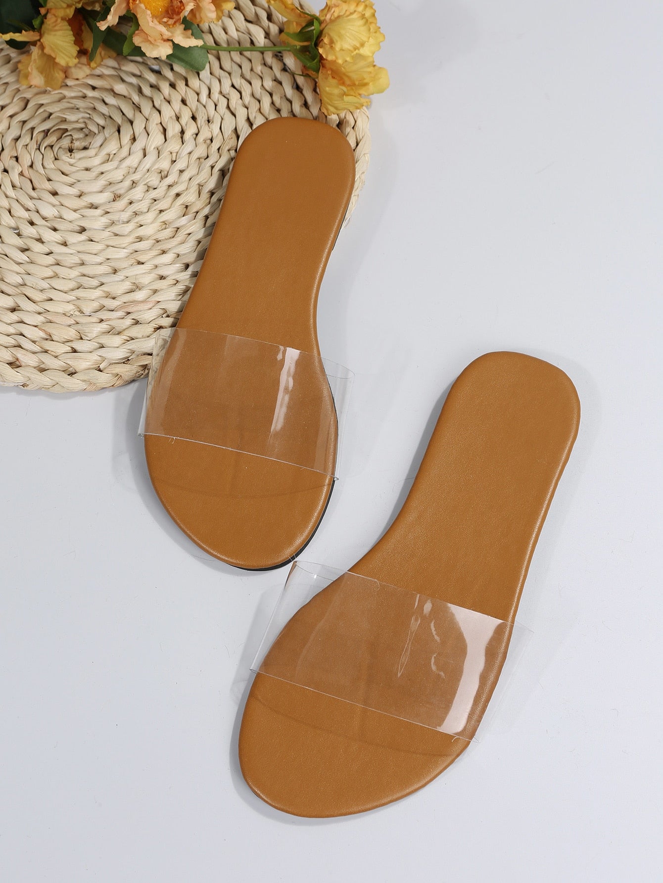 Women’s clear flat slide sandals with a single transparent band and open toe design.
