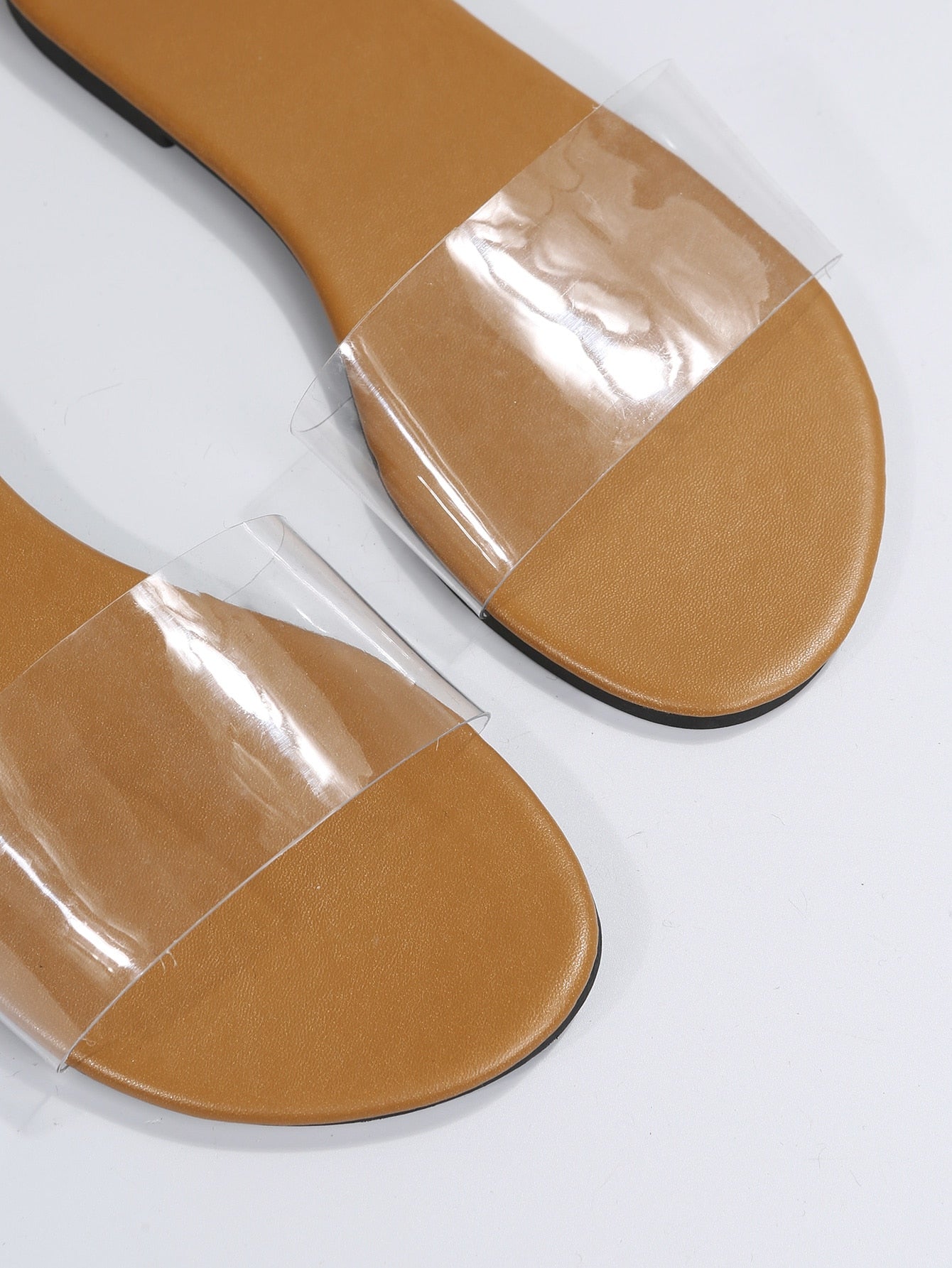 Women’s clear flat slide sandals with a single transparent band and open toe design.
