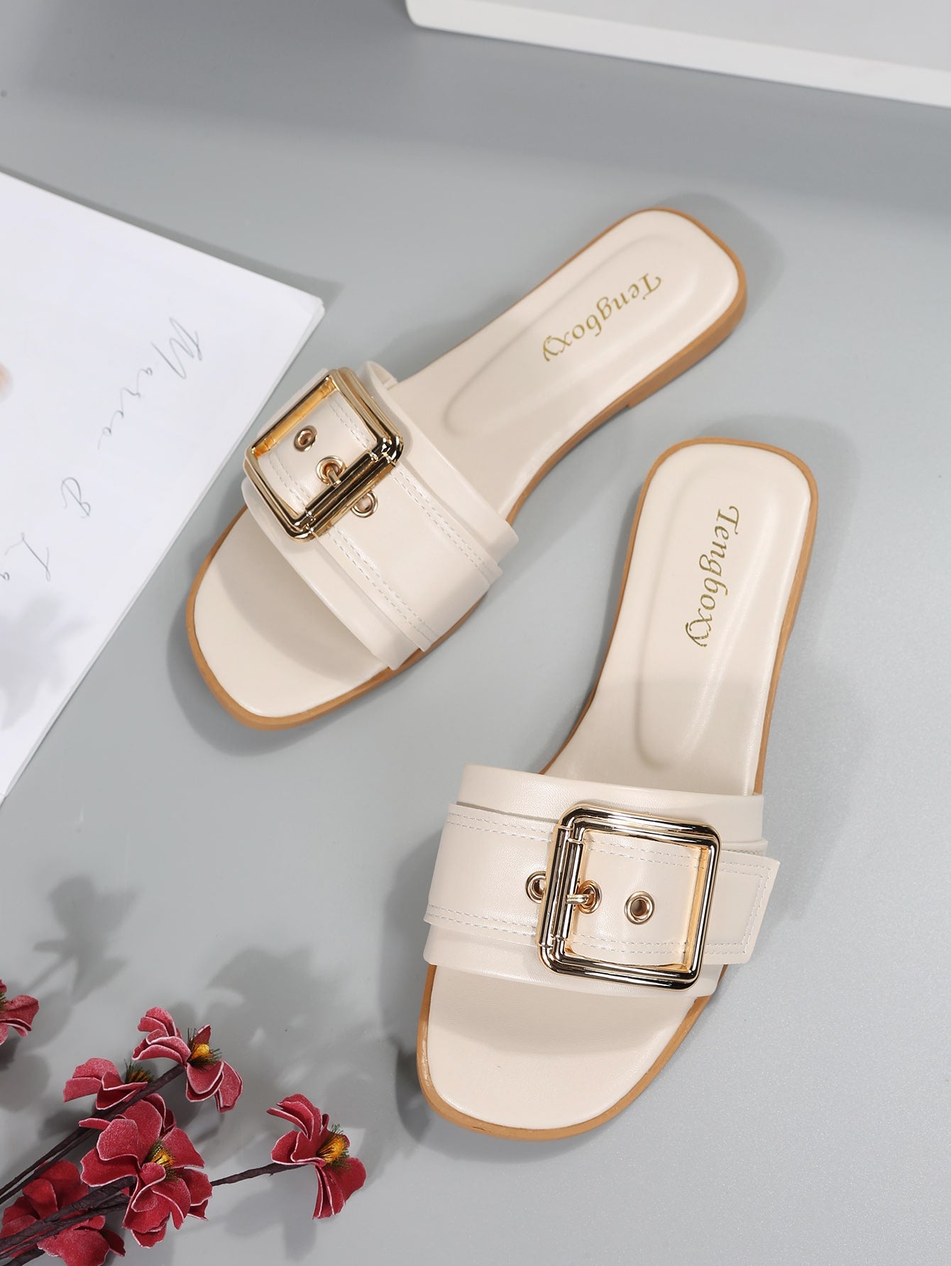 Women's beige flat slide sandals with open toe, cut-out upper, and square buckle detail, suitable for beach and summer outdoor wear.