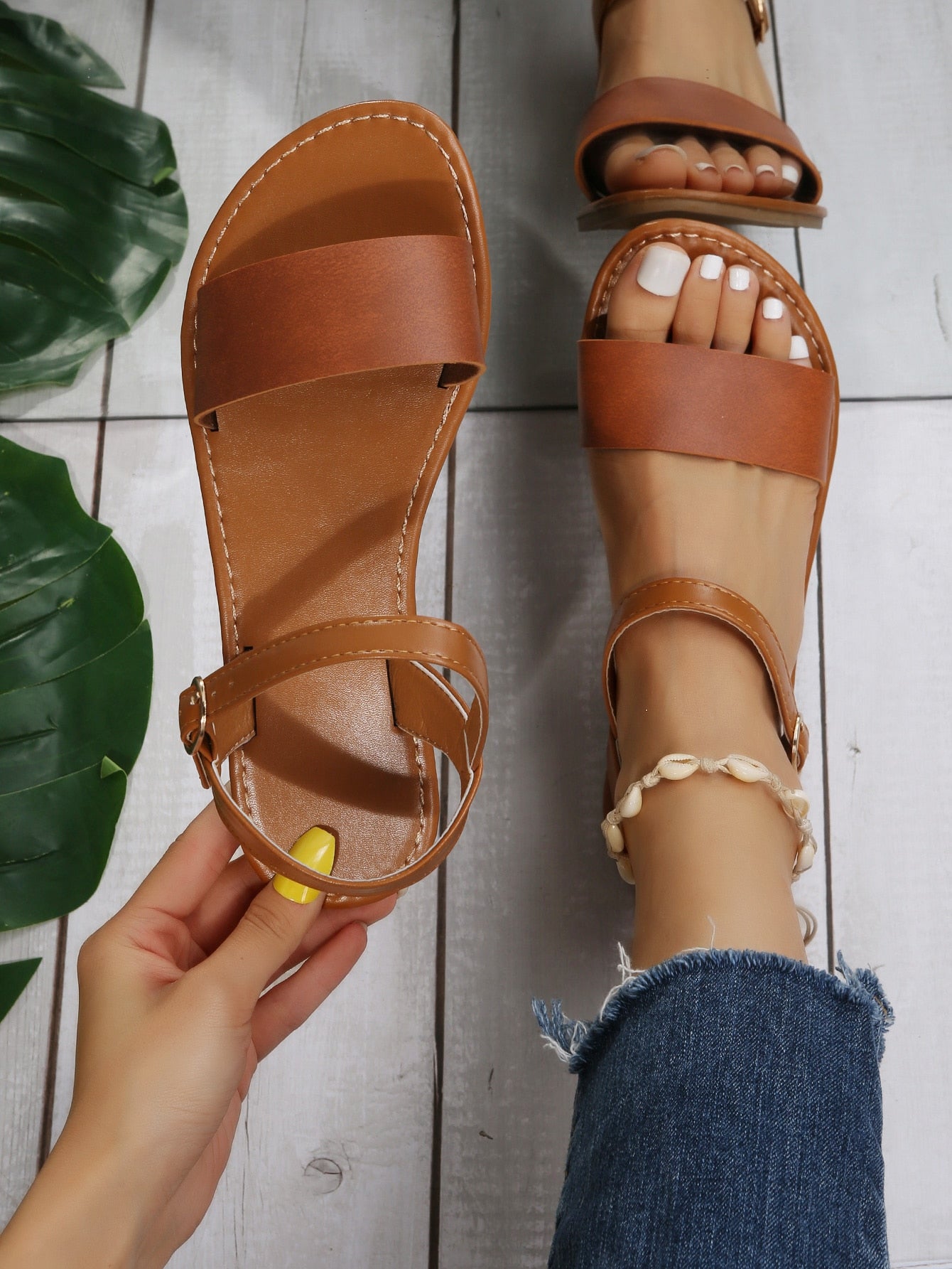 Leopard print flat sandals featuring an ankle strap with buckle detail, open toe design, and slide-style silhouette.