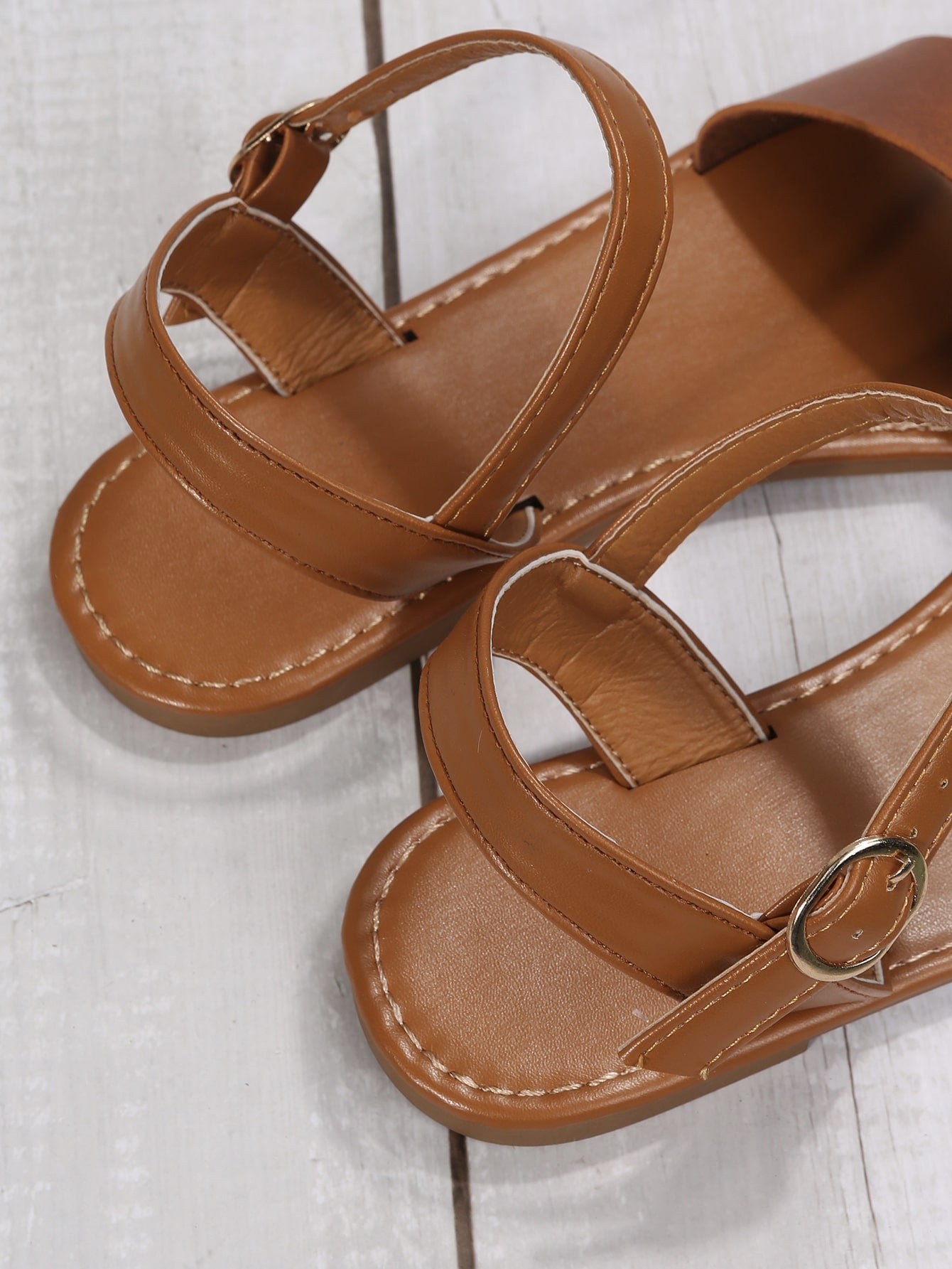 Leopard print flat sandals featuring an ankle strap with buckle detail, open toe design, and slide-style silhouette.
