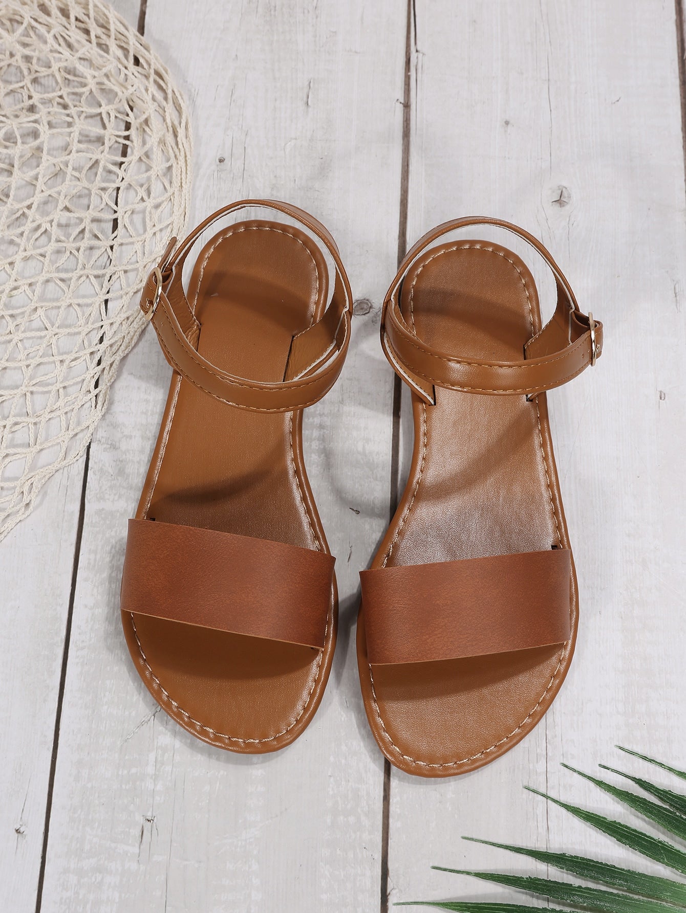 Leopard print flat sandals featuring an ankle strap with buckle detail, open toe design, and slide-style silhouette.