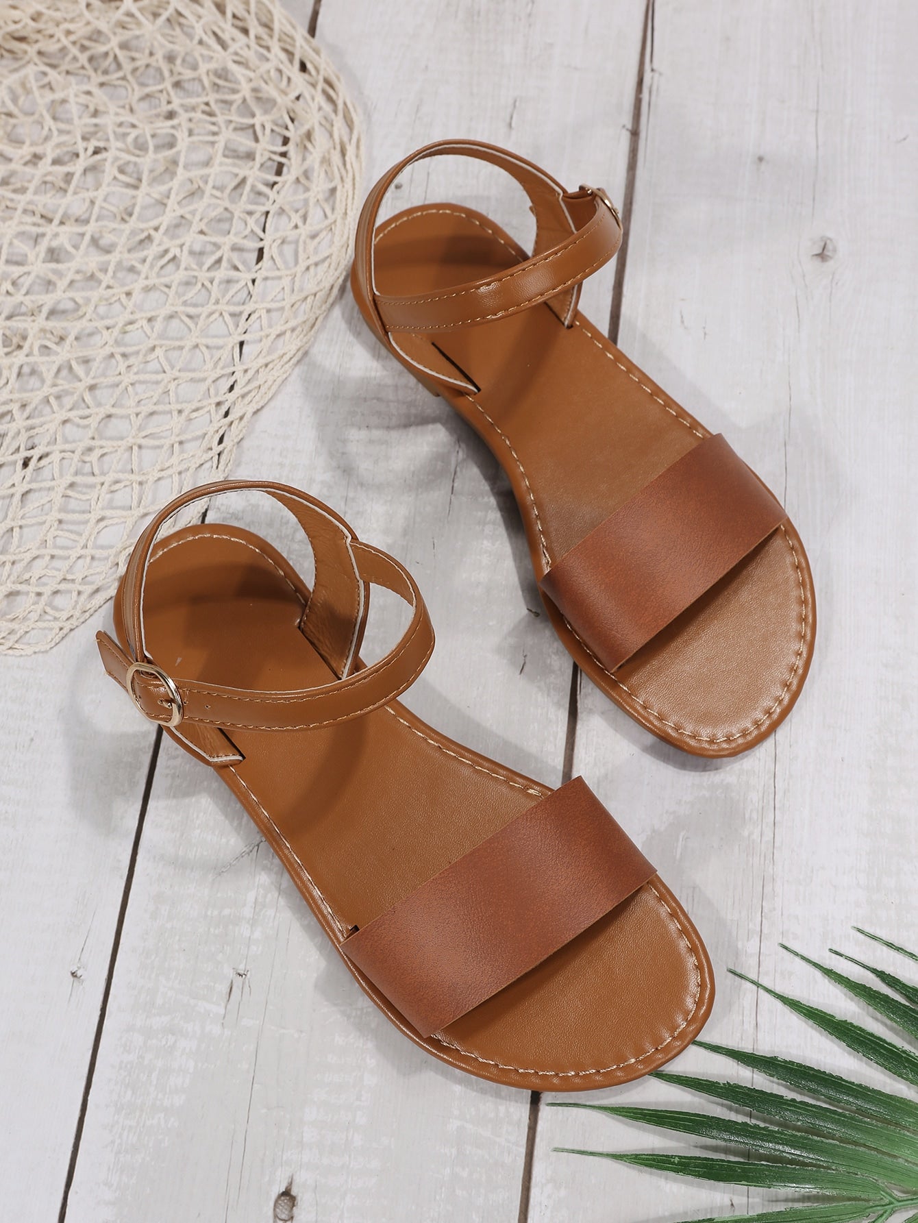 Leopard print flat sandals featuring an ankle strap with buckle detail, open toe design, and slide-style silhouette.
