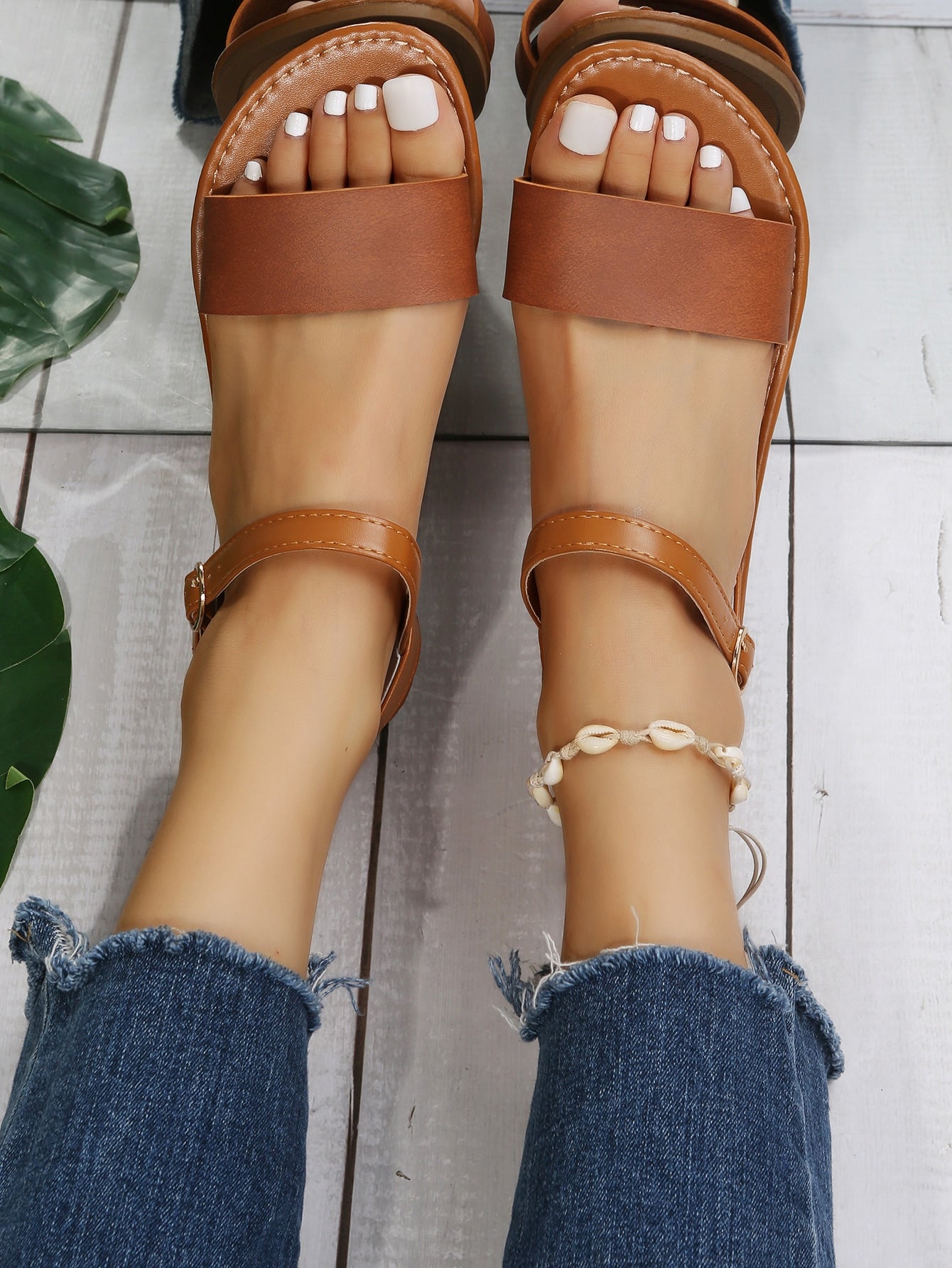 Leopard print flat sandals featuring an ankle strap with buckle detail, open toe design, and slide-style silhouette.