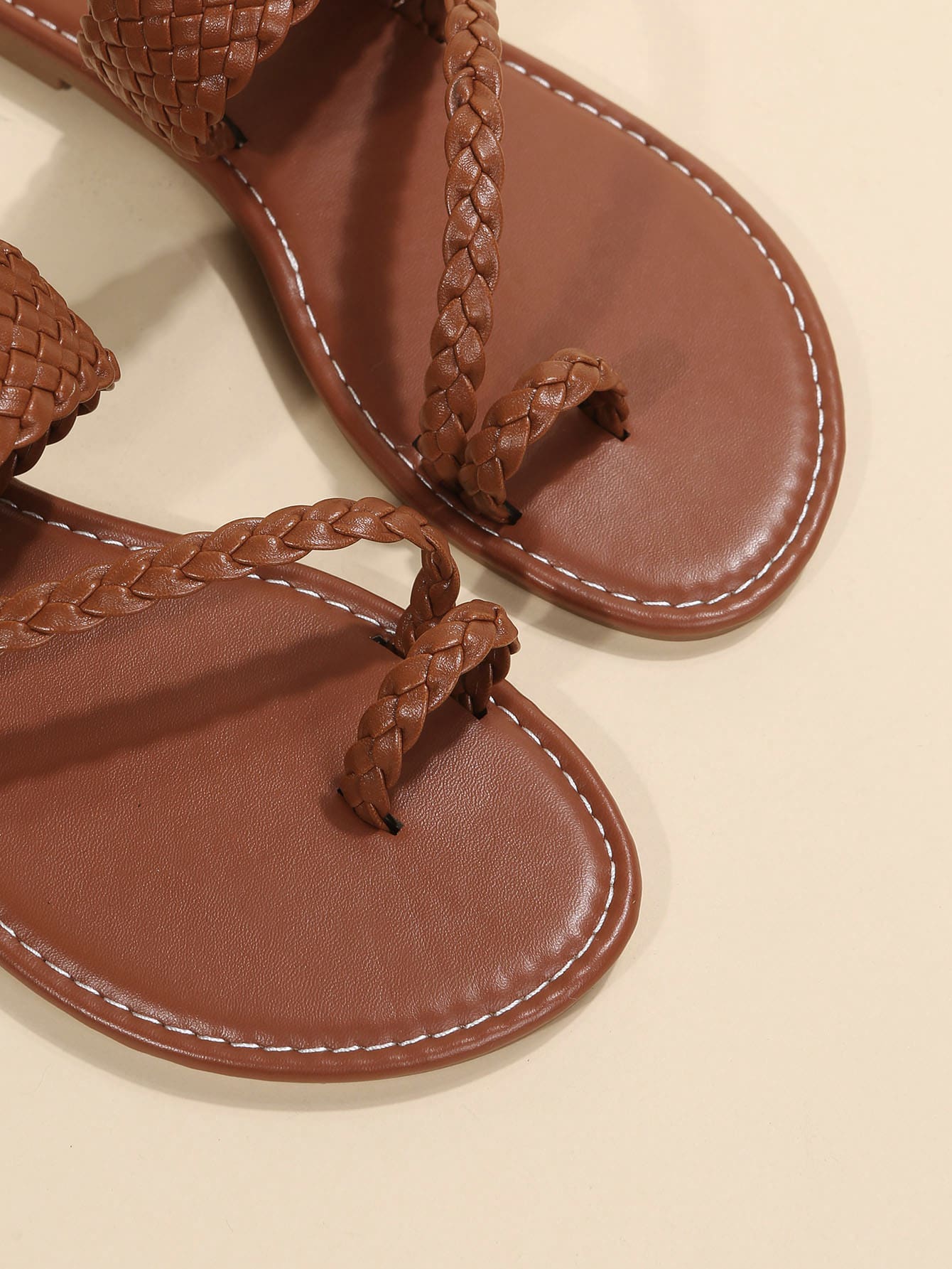 Women's brown flat thong sandals with braided straps, buckle detail, and toe post design for casual outdoor spring and summer wear.