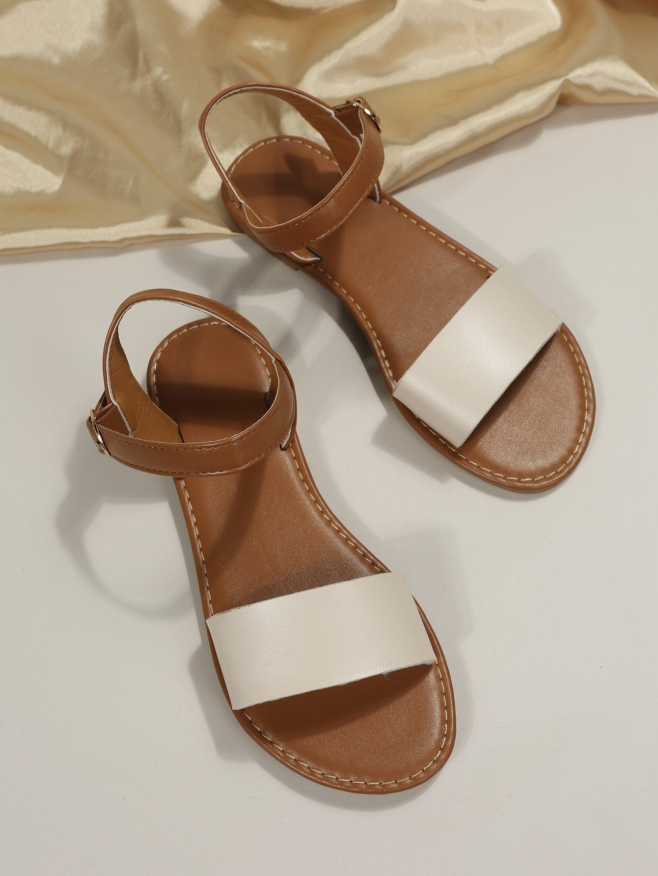 Leopard print flat sandals featuring an ankle strap with buckle detail, open toe design, and slide-style silhouette.