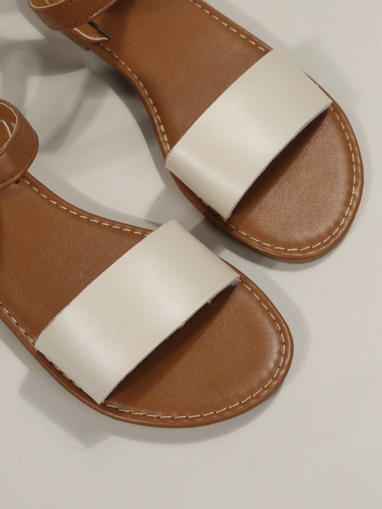Leopard print flat sandals featuring an ankle strap with buckle detail, open toe design, and slide-style silhouette.
