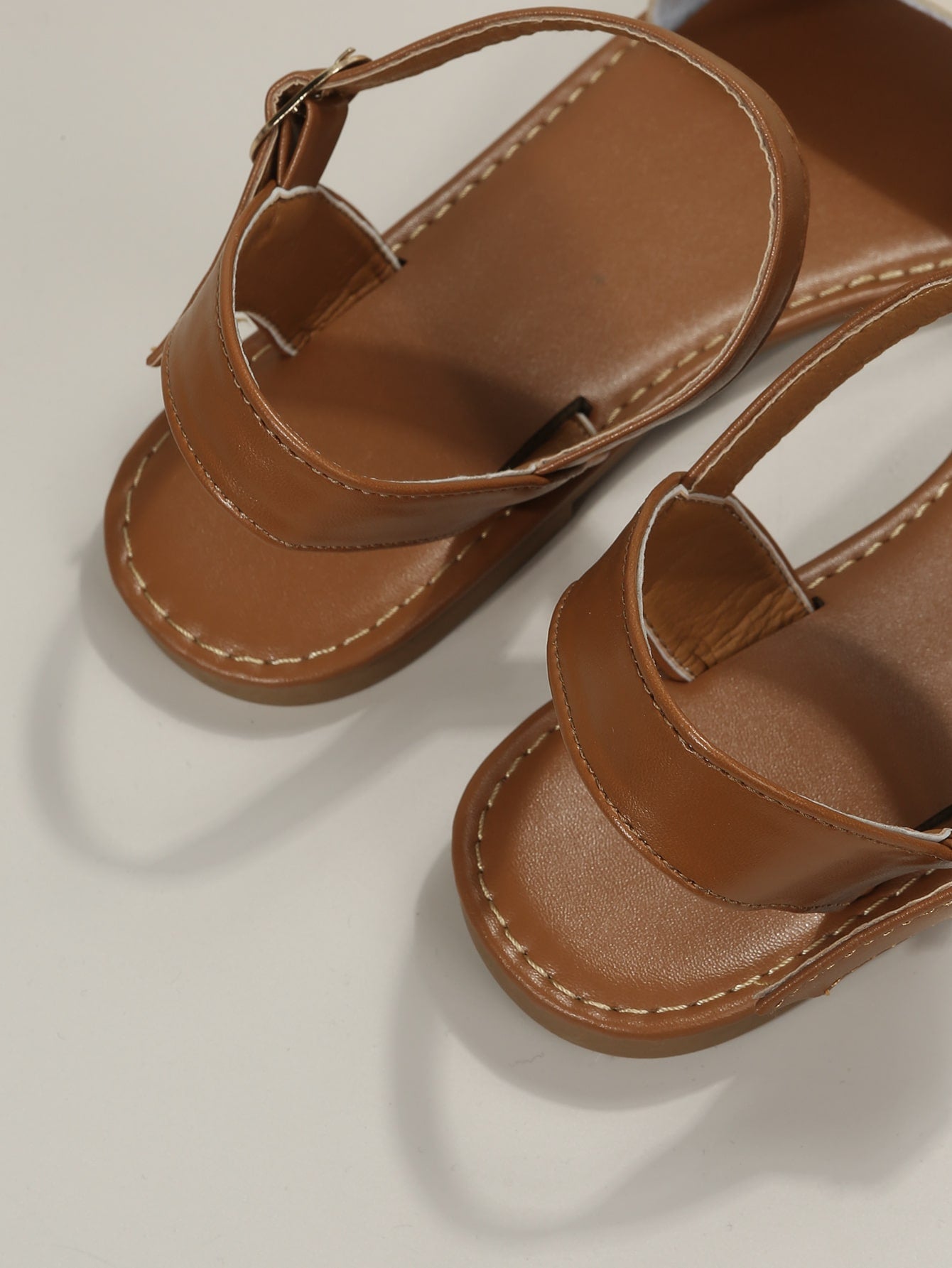 Leopard print flat sandals featuring an ankle strap with buckle detail, open toe design, and slide-style silhouette.