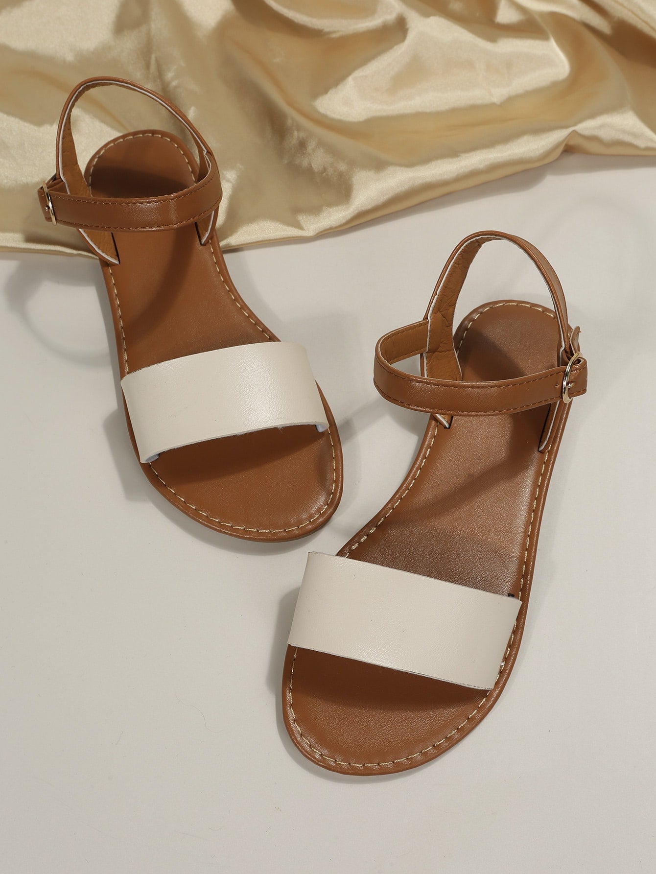Leopard print flat sandals featuring an ankle strap with buckle detail, open toe design, and slide-style silhouette.