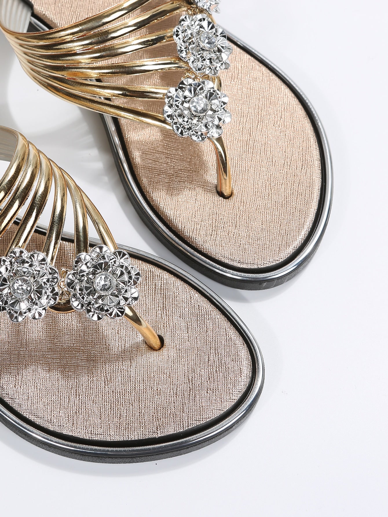 Women’s gold metallic flat thong sandals with rhinestone and flower decor, toe post design, and beach-ready style.