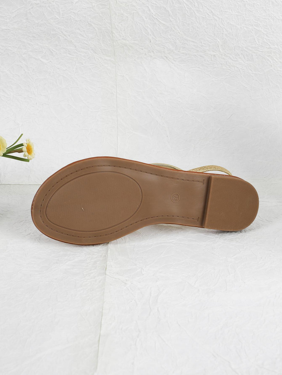 Pair of women’s gold flat sandals featuring a toe ring thong toe post design, criss-cross straps, and a slingback ankle strap.