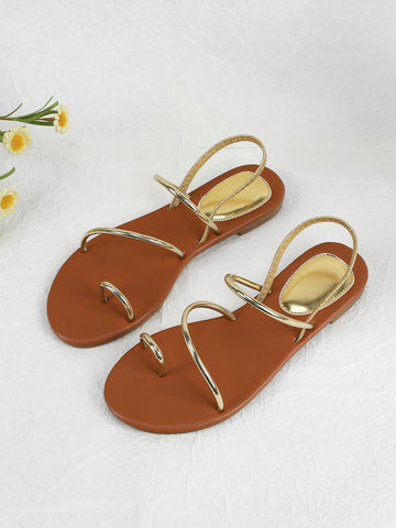 Pair of women’s gold flat sandals featuring a toe ring thong toe post design, criss-cross straps, and a slingback ankle strap.