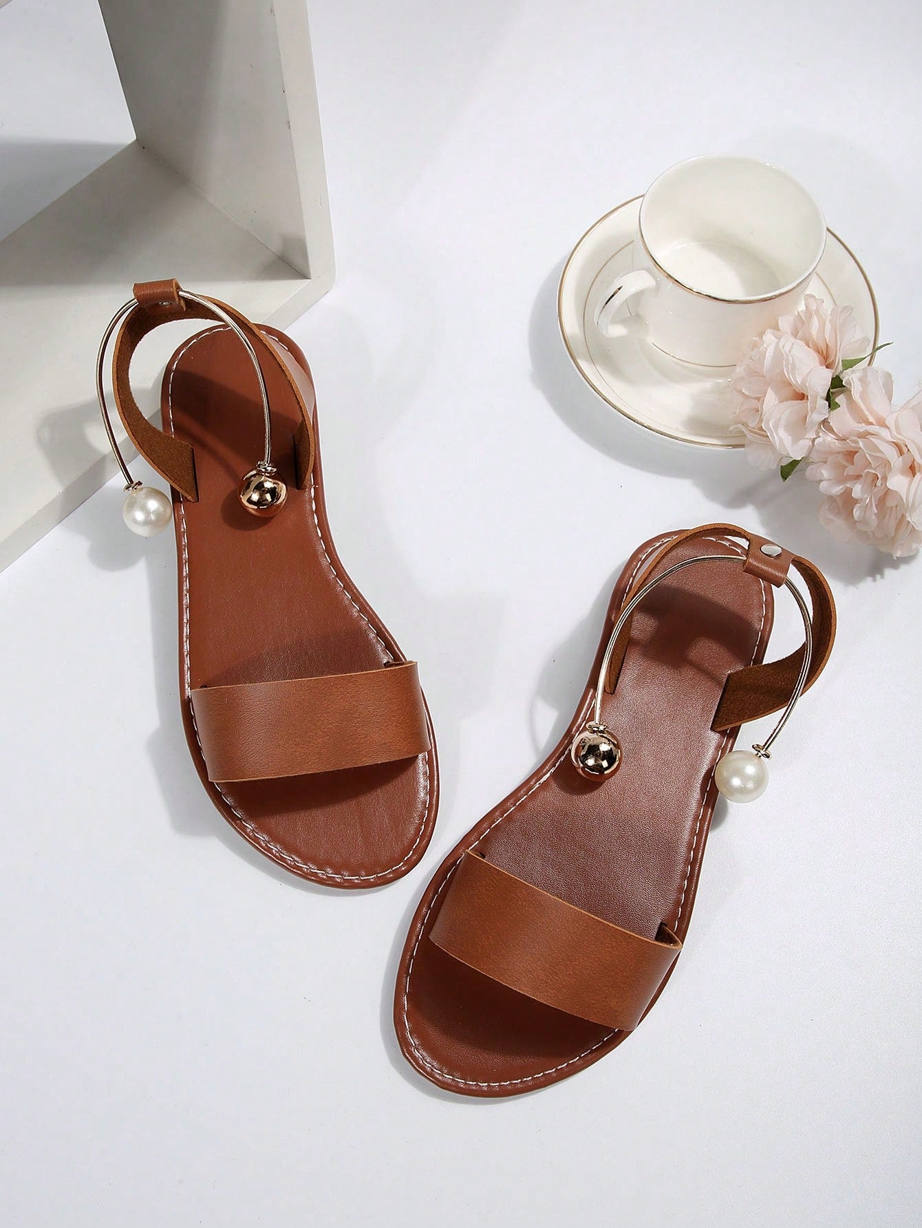 Women’s flat open-toe sandals with faux pearl decor and ankle strap design, featuring a microfiber leather upper and beach-ready fashion style.