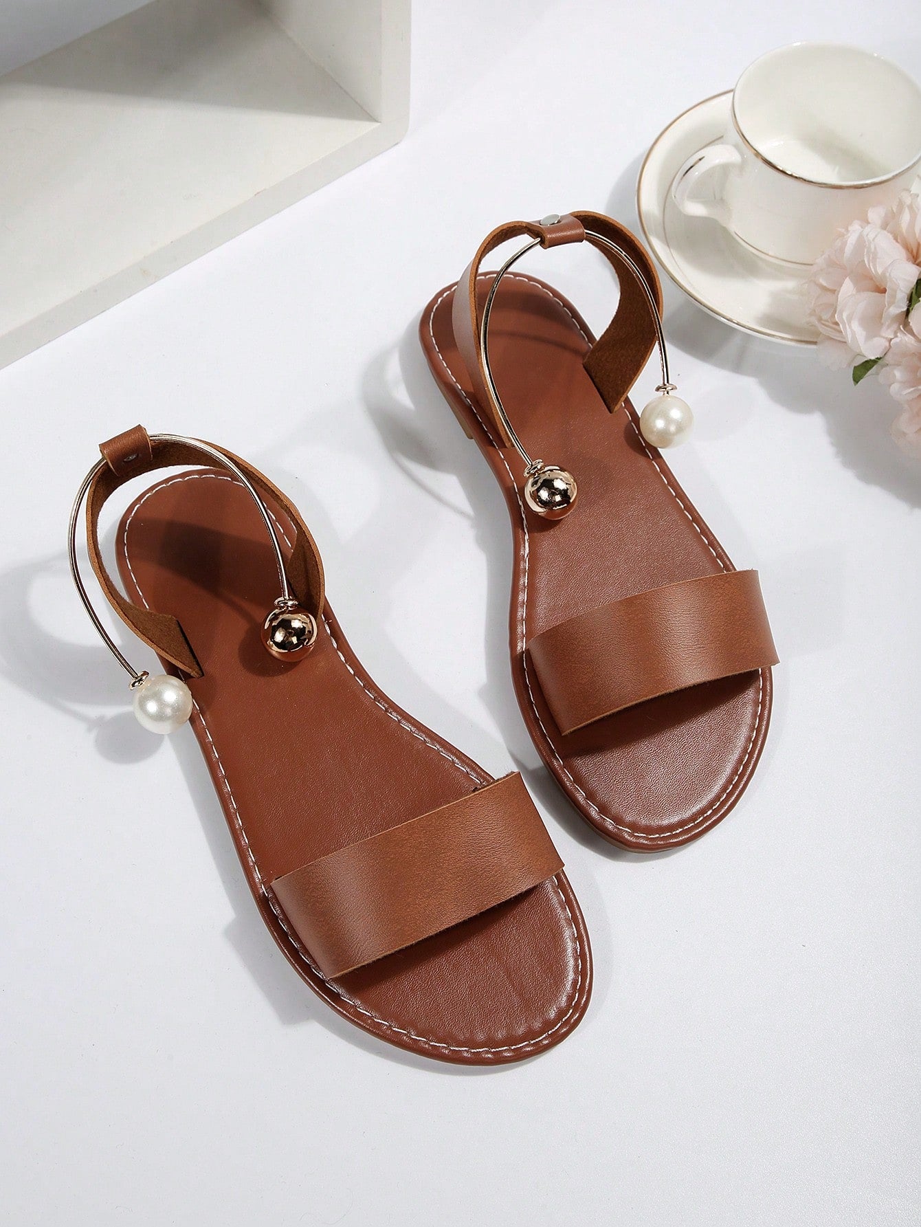 Women’s flat open-toe sandals with faux pearl decor and ankle strap design, featuring a microfiber leather upper and beach-ready fashion style.