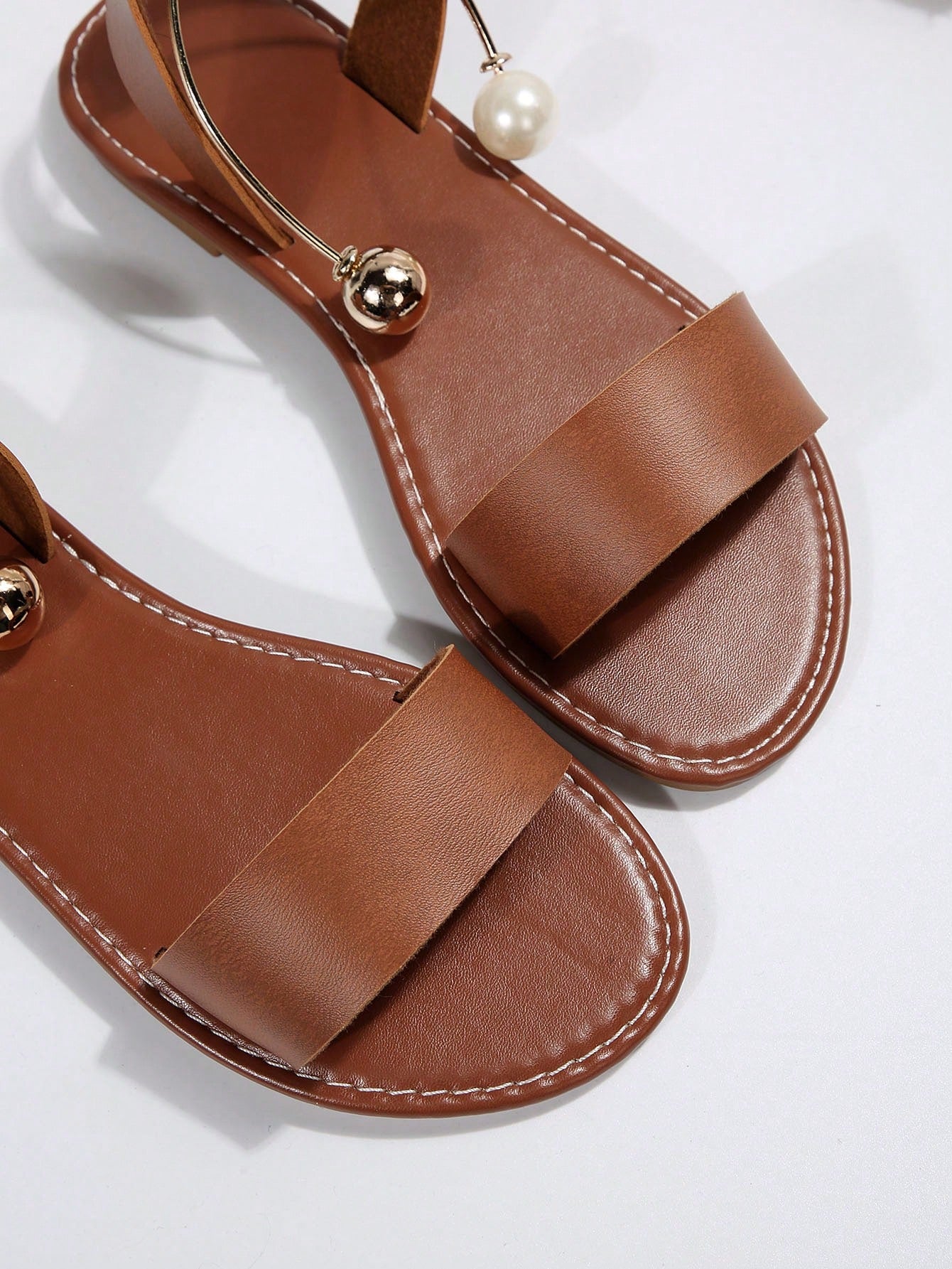 Women’s flat open-toe sandals with faux pearl decor and ankle strap design, featuring a microfiber leather upper and beach-ready fashion style.