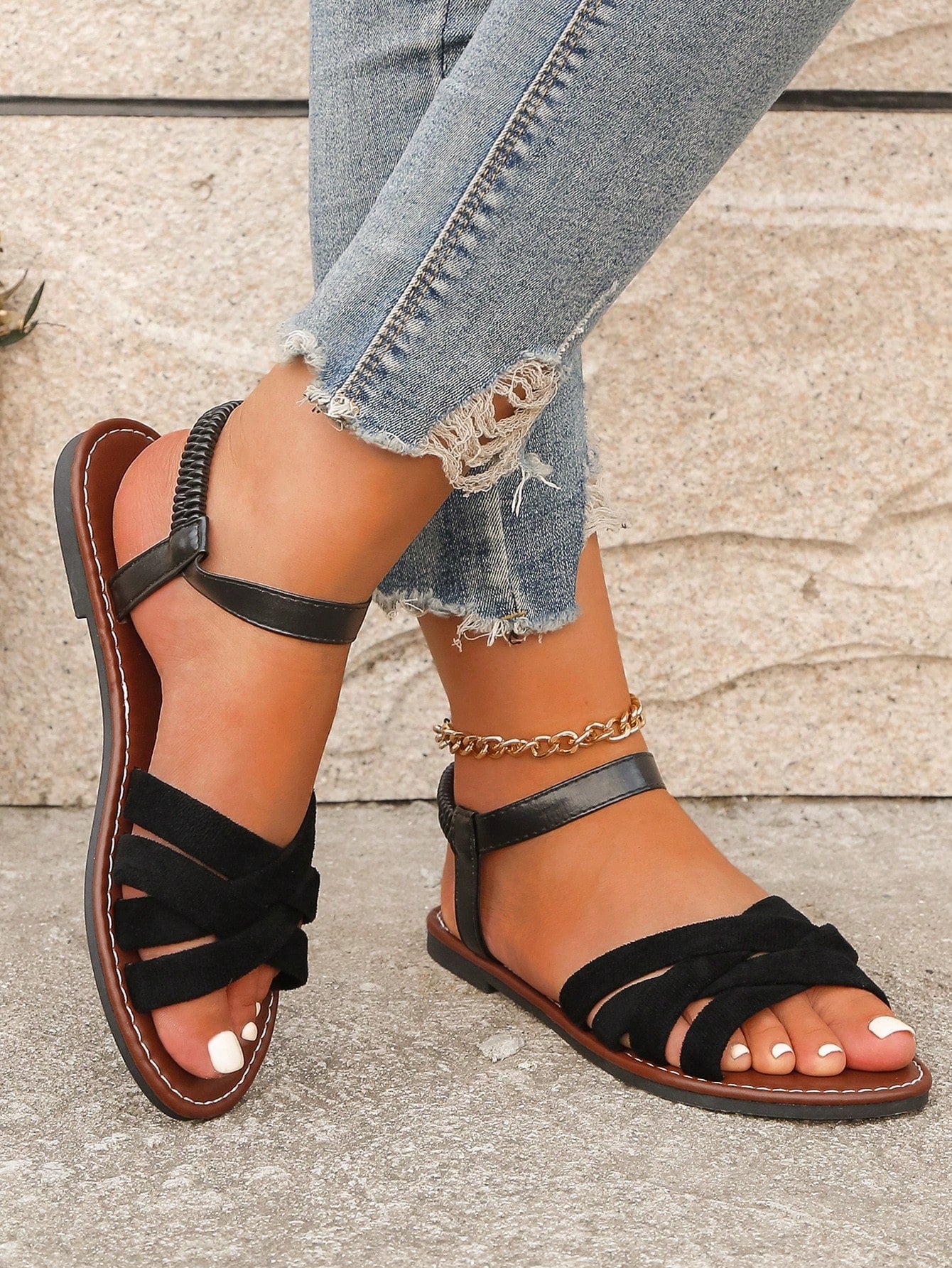 Women's black flat sandals with criss cross straps, ankle strap with buckle, and open toe design