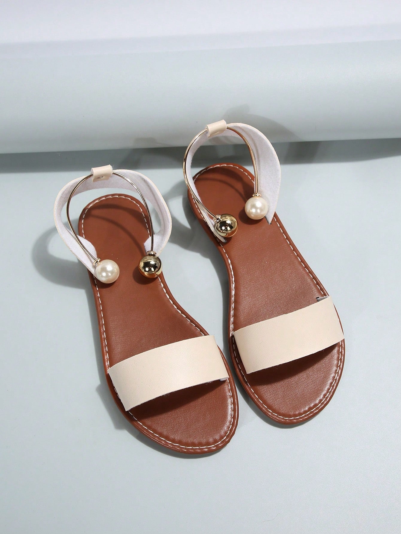 Women’s flat open-toe sandals with faux pearl decor and ankle strap design, featuring a microfiber leather upper and beach-ready fashion style.