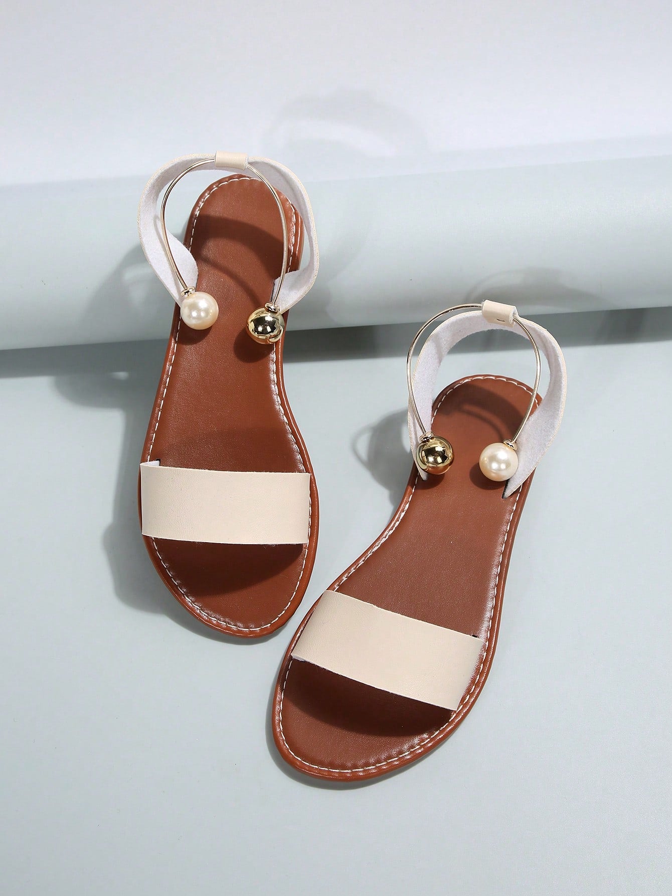 Women’s flat open-toe sandals with faux pearl decor and ankle strap design, featuring a microfiber leather upper and beach-ready fashion style.