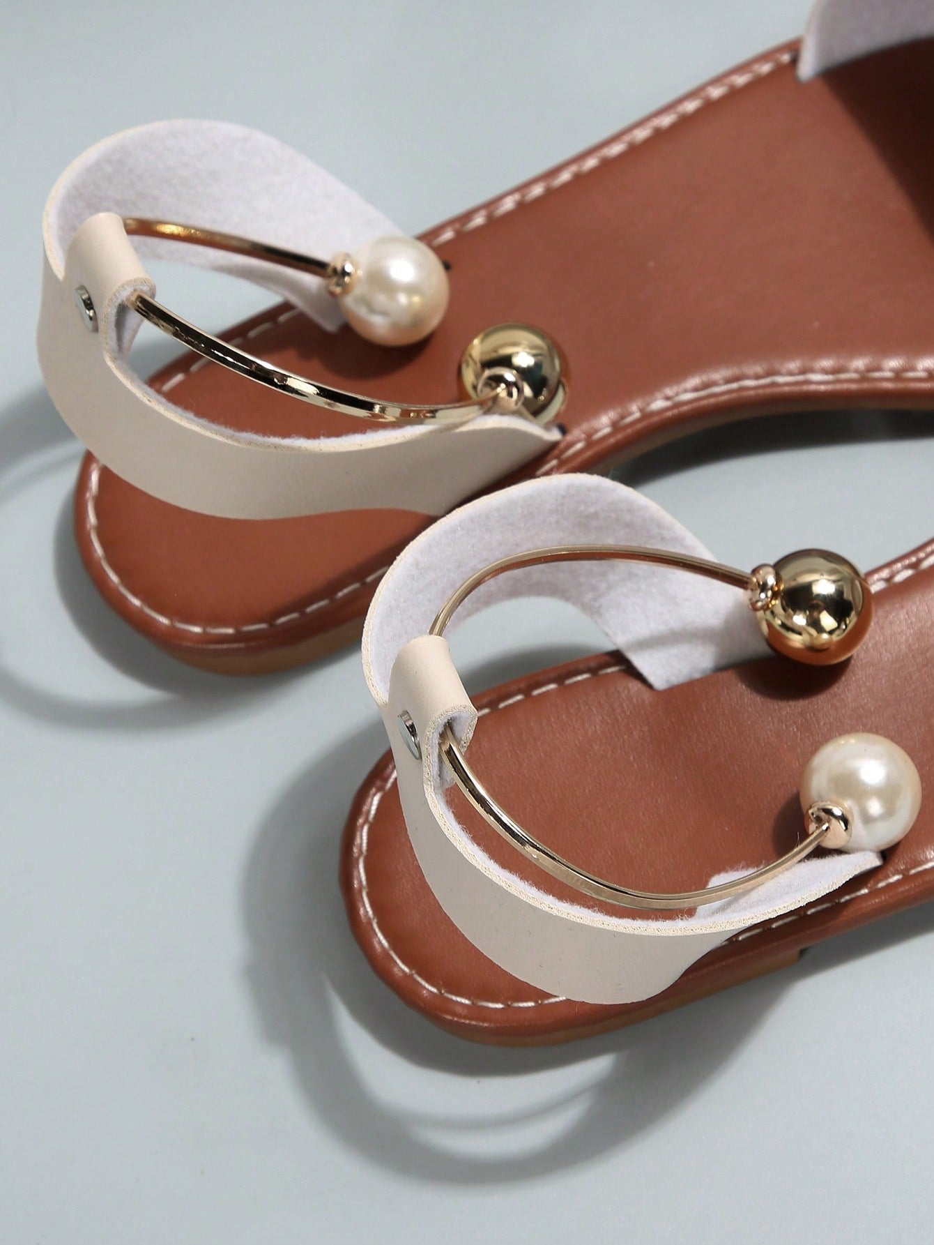 Women’s flat open-toe sandals with faux pearl decor and ankle strap design, featuring a microfiber leather upper and beach-ready fashion style.