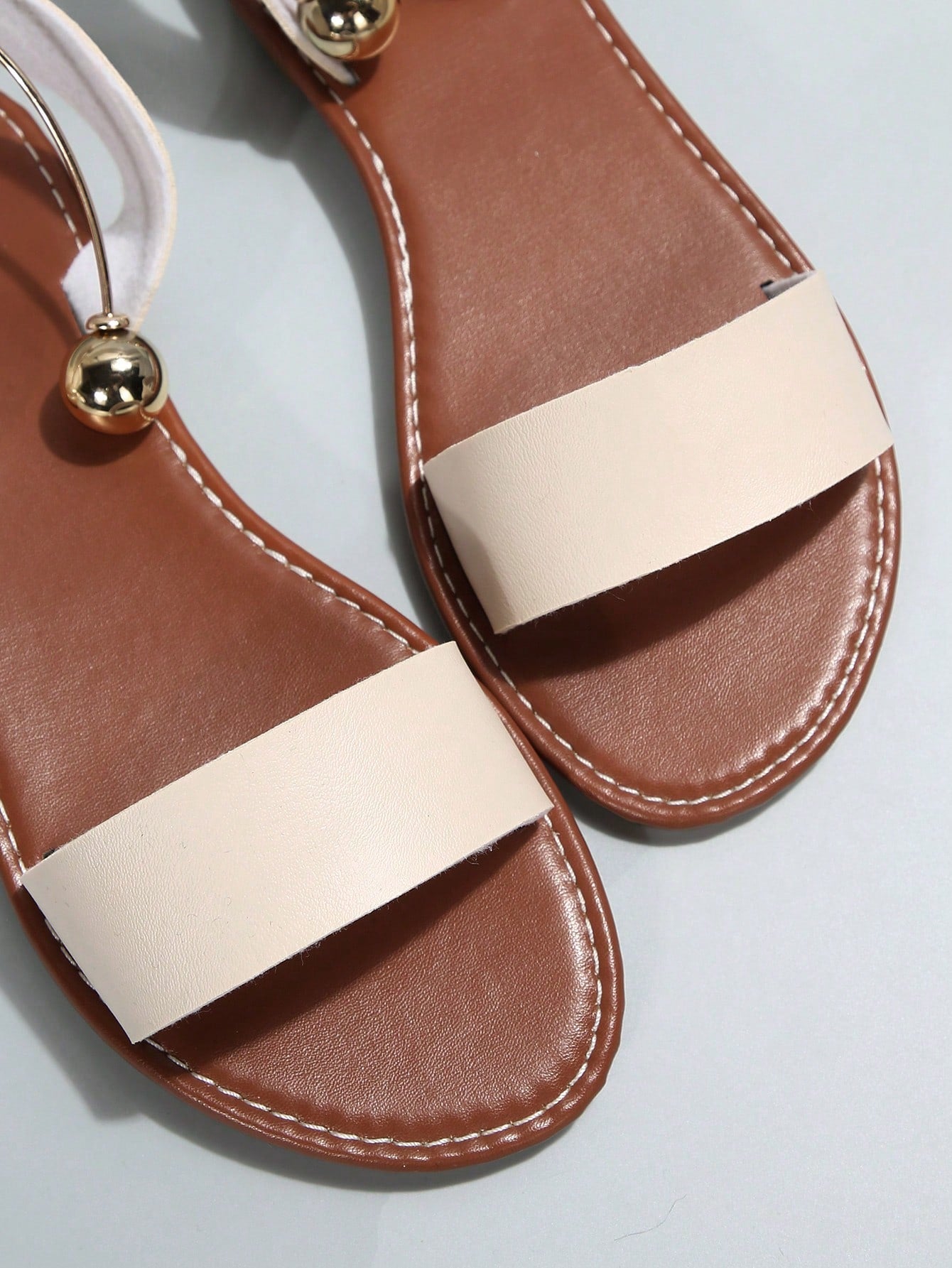 Women’s flat open-toe sandals with faux pearl decor and ankle strap design, featuring a microfiber leather upper and beach-ready fashion style.