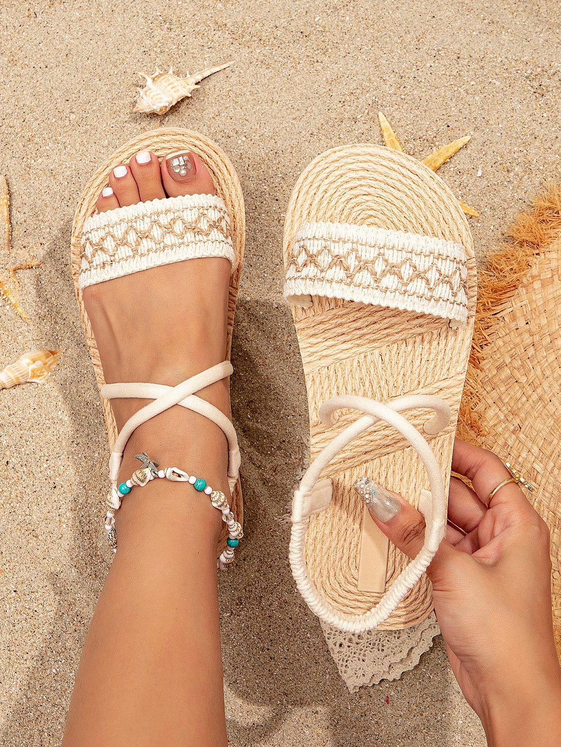 Women’s beige cross strap flat sandals with ankle strap, exposed heel, and fringe detail, suitable for beach and vacation wear.