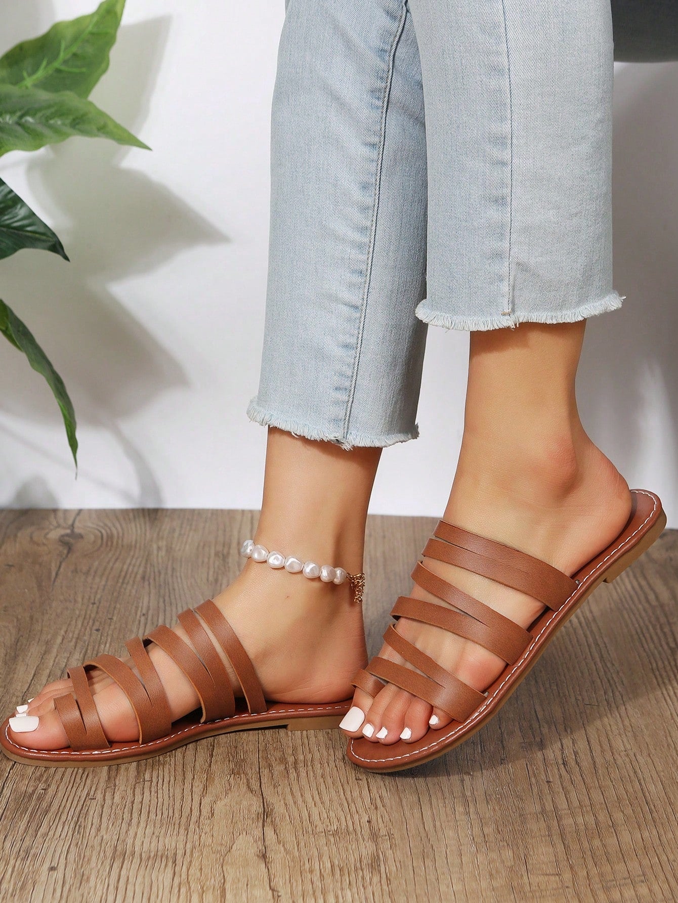 Women’s brown flat sandals with toe post and cross-over straps in a bohemian slide style