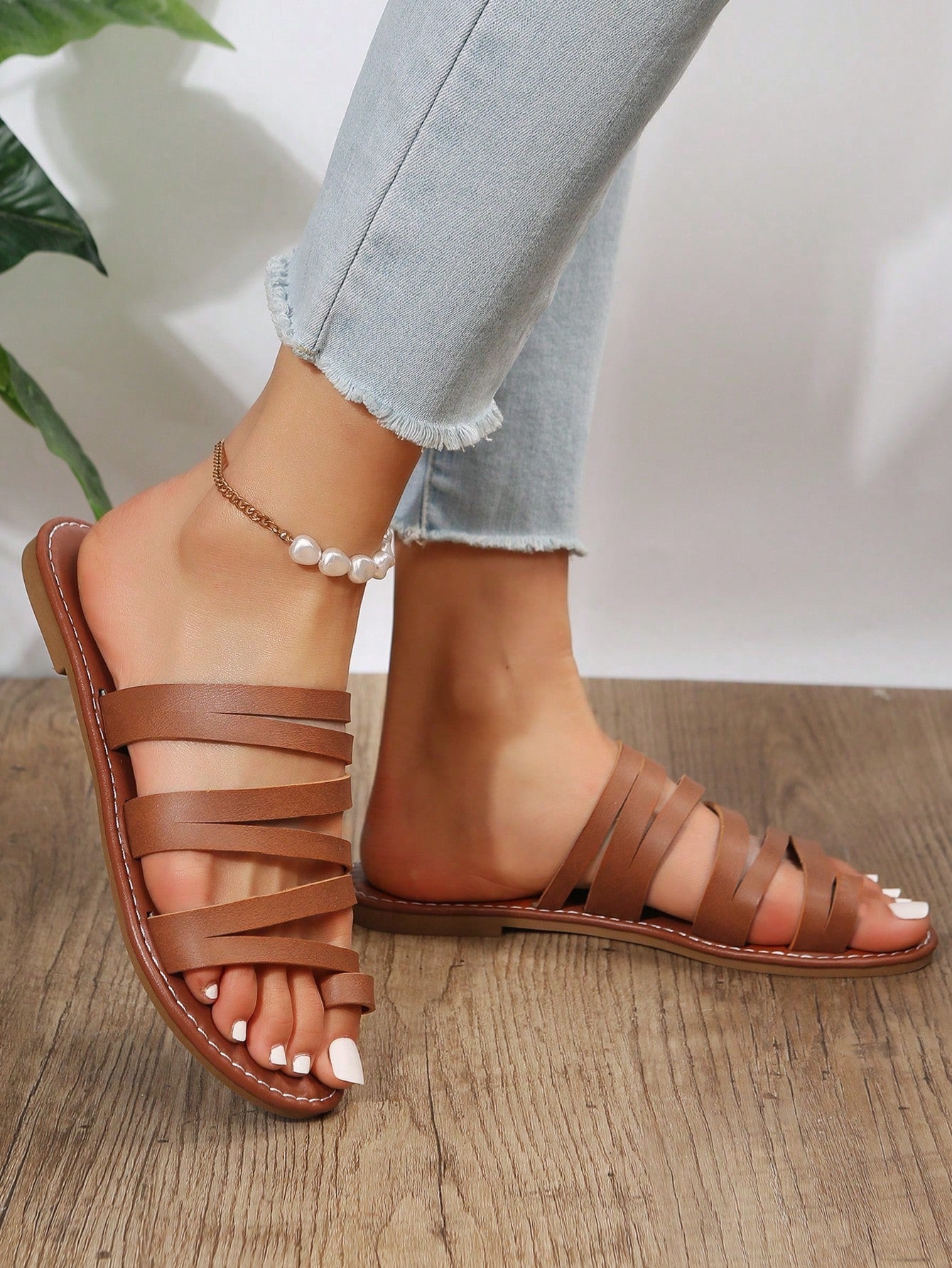 Women’s brown flat sandals with toe post and cross-over straps in a bohemian slide style