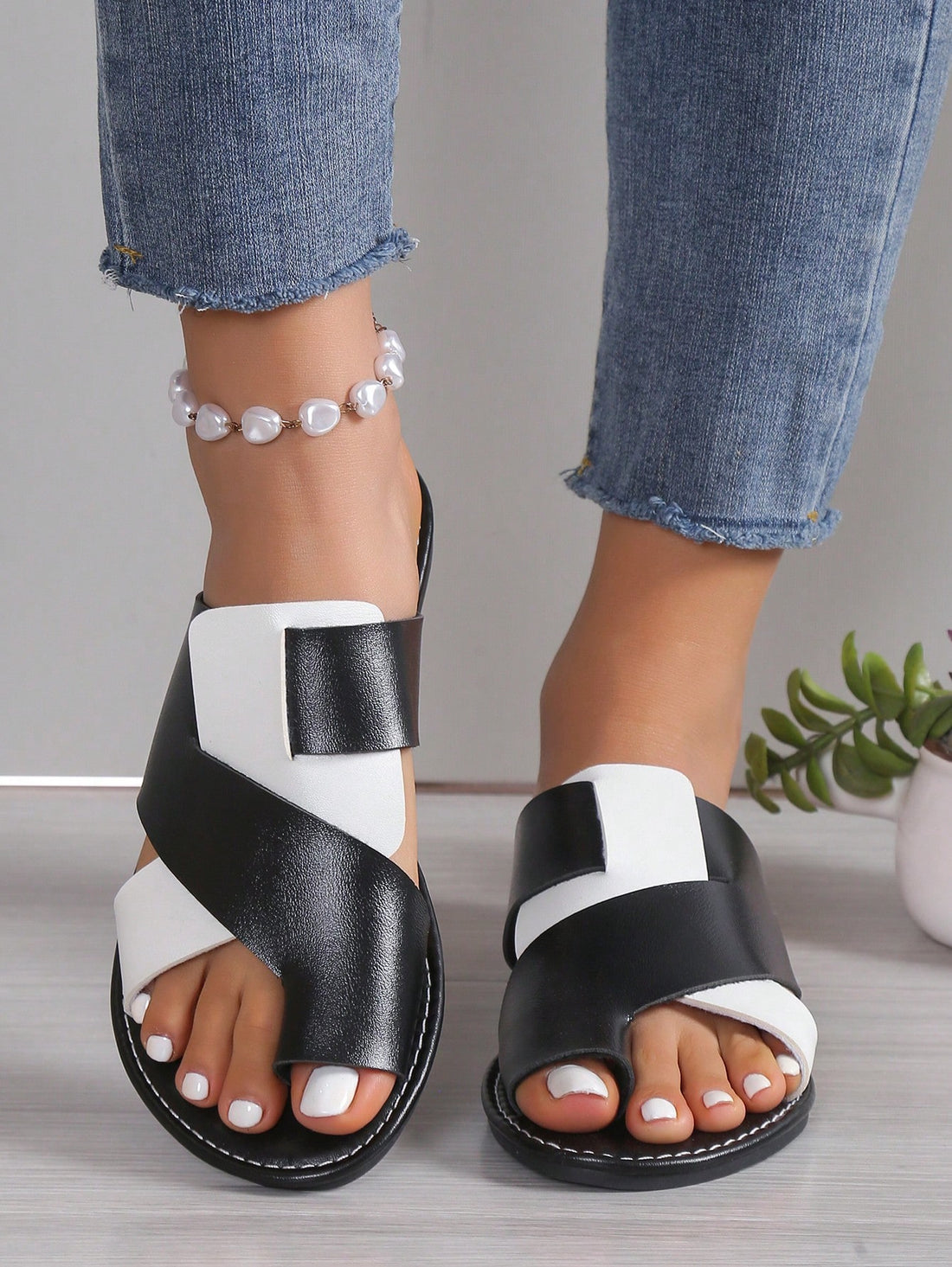 Women's flat colorblock flip flop sandals in black and white with toe post design and slip-on style.