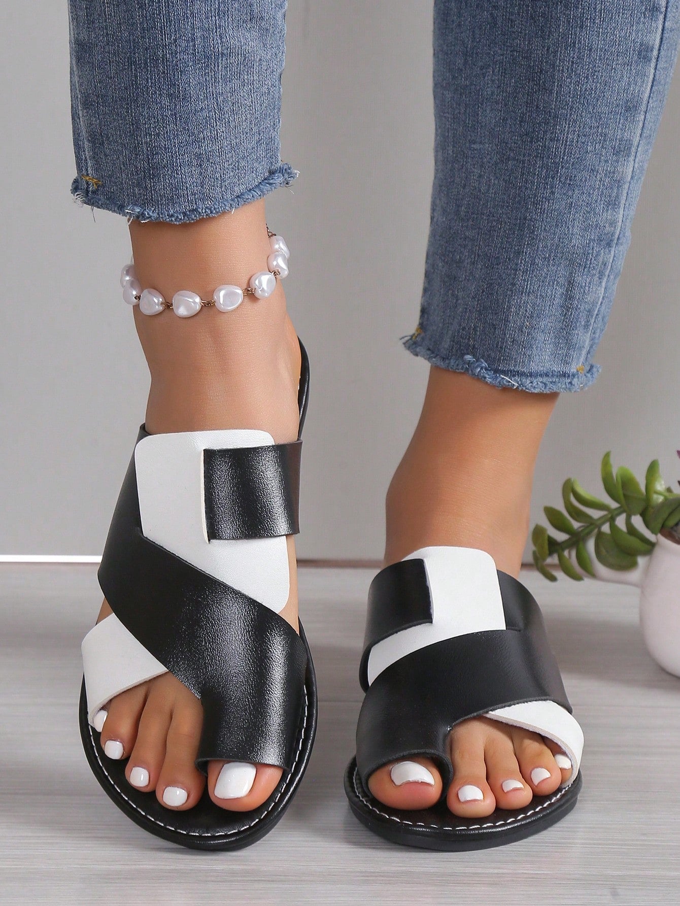 Women's flat colorblock flip flop sandals in black and white with toe post design and slip-on style.