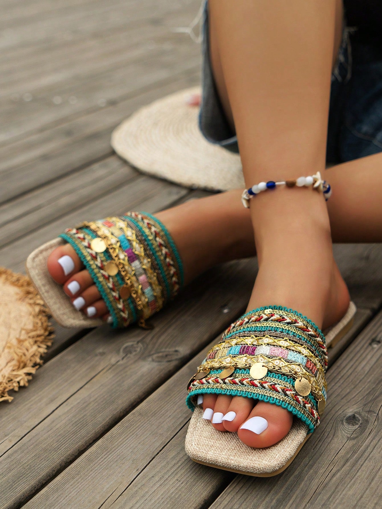 Pair of green women’s flat slide sandals with open toes, embroidered and beaded detailing, and fringe accents in a vacation style.