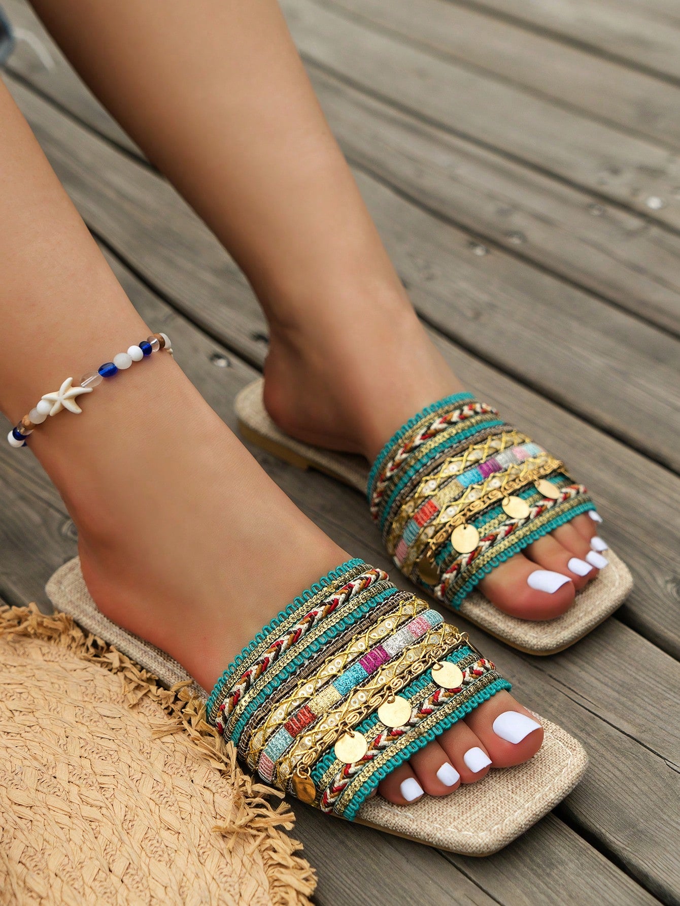 Pair of green women’s flat slide sandals with open toes, embroidered and beaded detailing, and fringe accents in a vacation style.