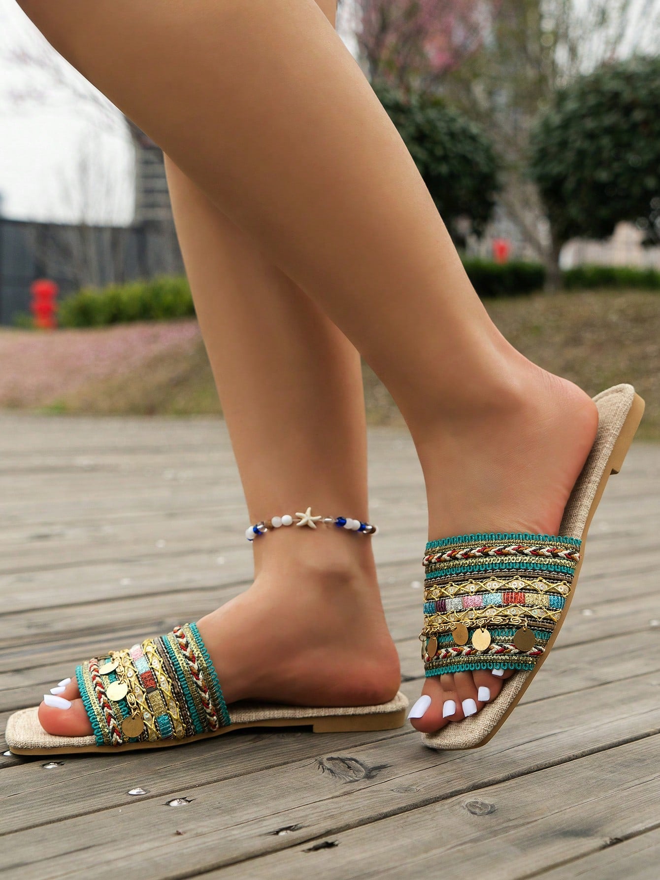 Pair of green women’s flat slide sandals with open toes, embroidered and beaded detailing, and fringe accents in a vacation style.