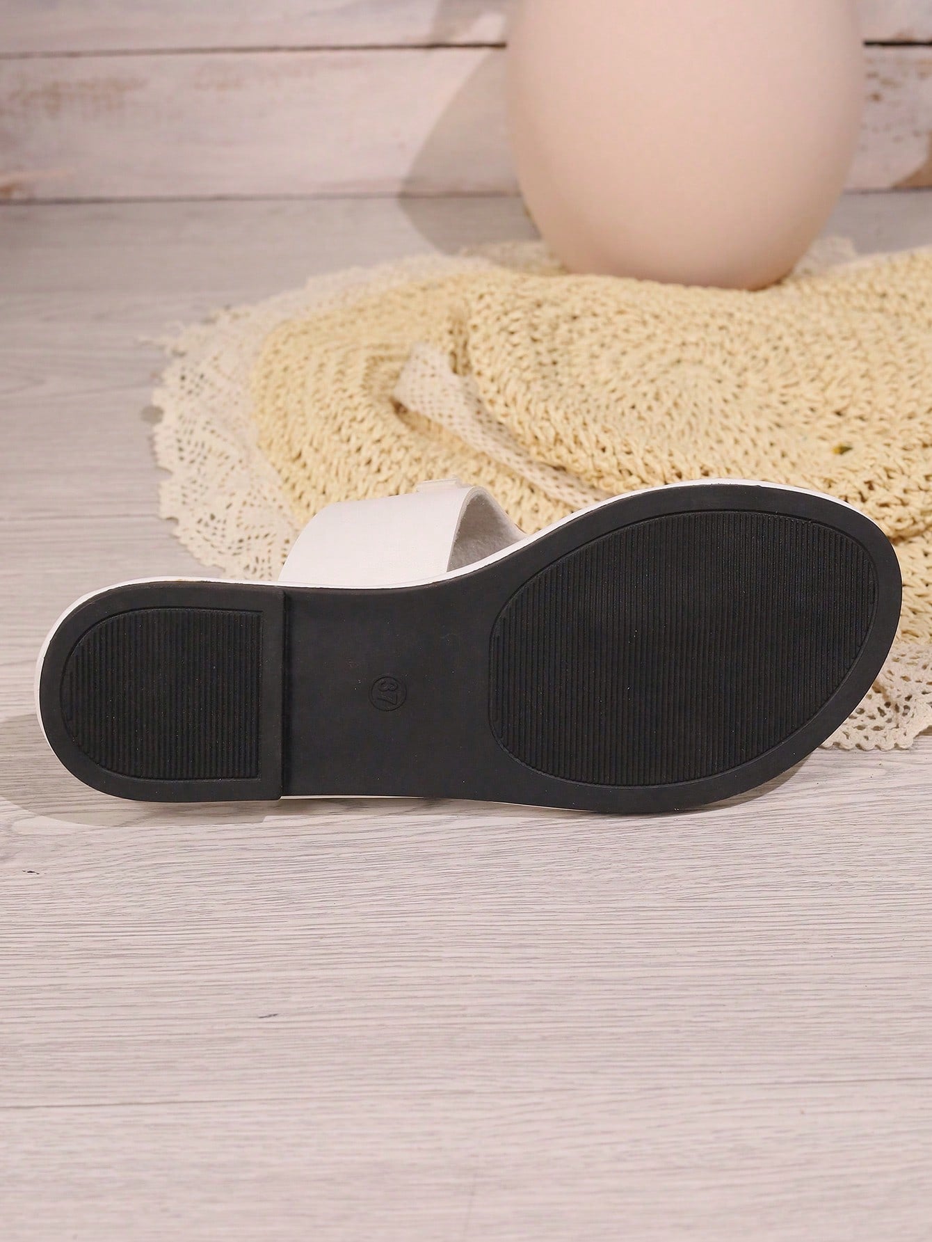 Women's flat slide sandals with toe post strap, cut-out pattern, and metal detail, designed with a lightweight cushioned sole for casual beach and vacation use.