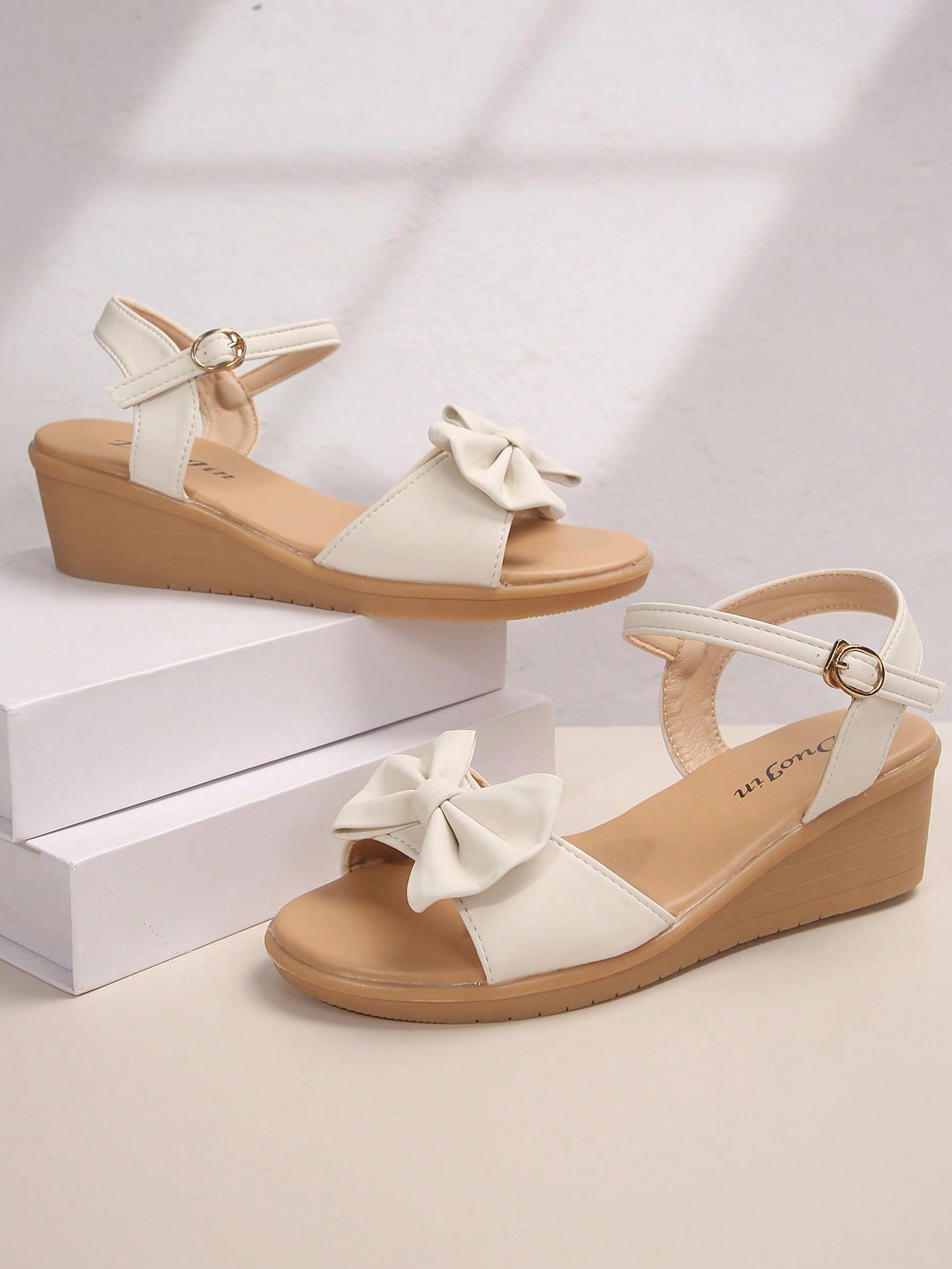 Women's open-toe wedge sandals featuring a thick sole, mid wedge heel, bowknot detail, and single buckle ankle strap.