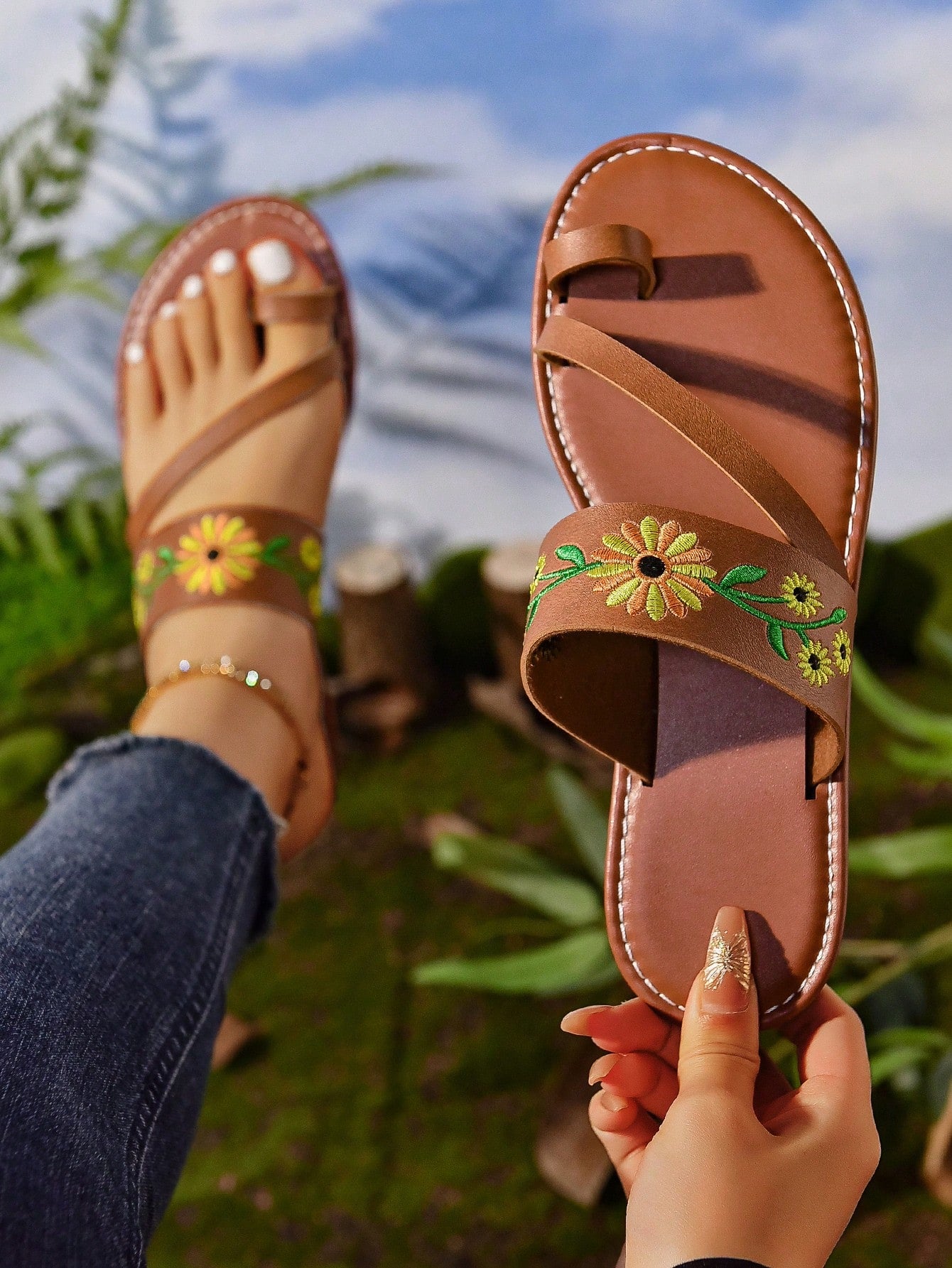 Women's mocha brown flat toe-post flip flops with sunflower design, woven slingback strap, and buckle chain detail, styled as comfortable beach sandals.