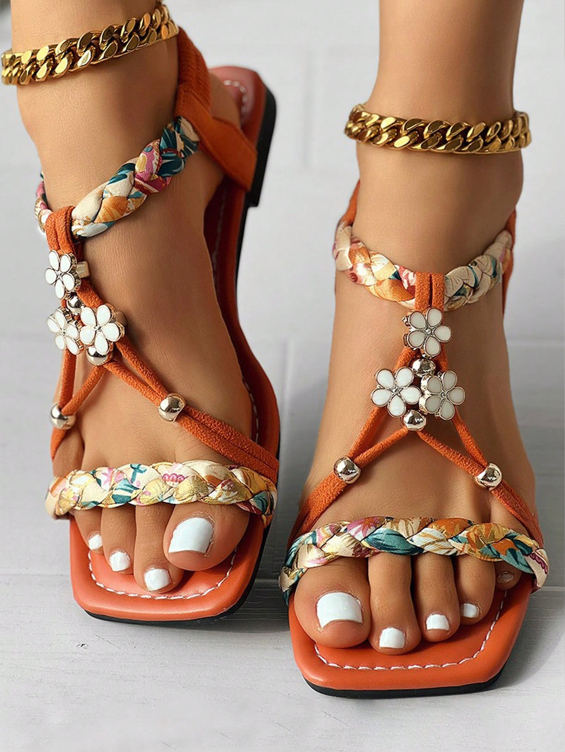 Women's orange flat slide sandals with beaded rhinestone and braided details in a Roman-inspired boho style, featuring an open toe design.