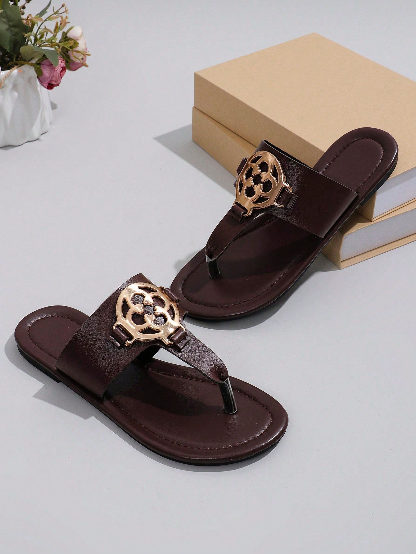 Women's flat slide sandals with toe post strap, cut-out pattern, and metal detail, designed with a lightweight cushioned sole for casual beach and vacation use.