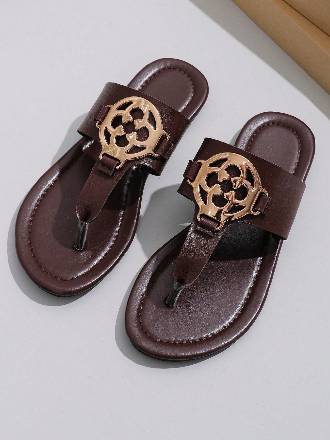 Women's flat slide sandals with toe post strap, cut-out pattern, and metal detail, designed with a lightweight cushioned sole for casual beach and vacation use.