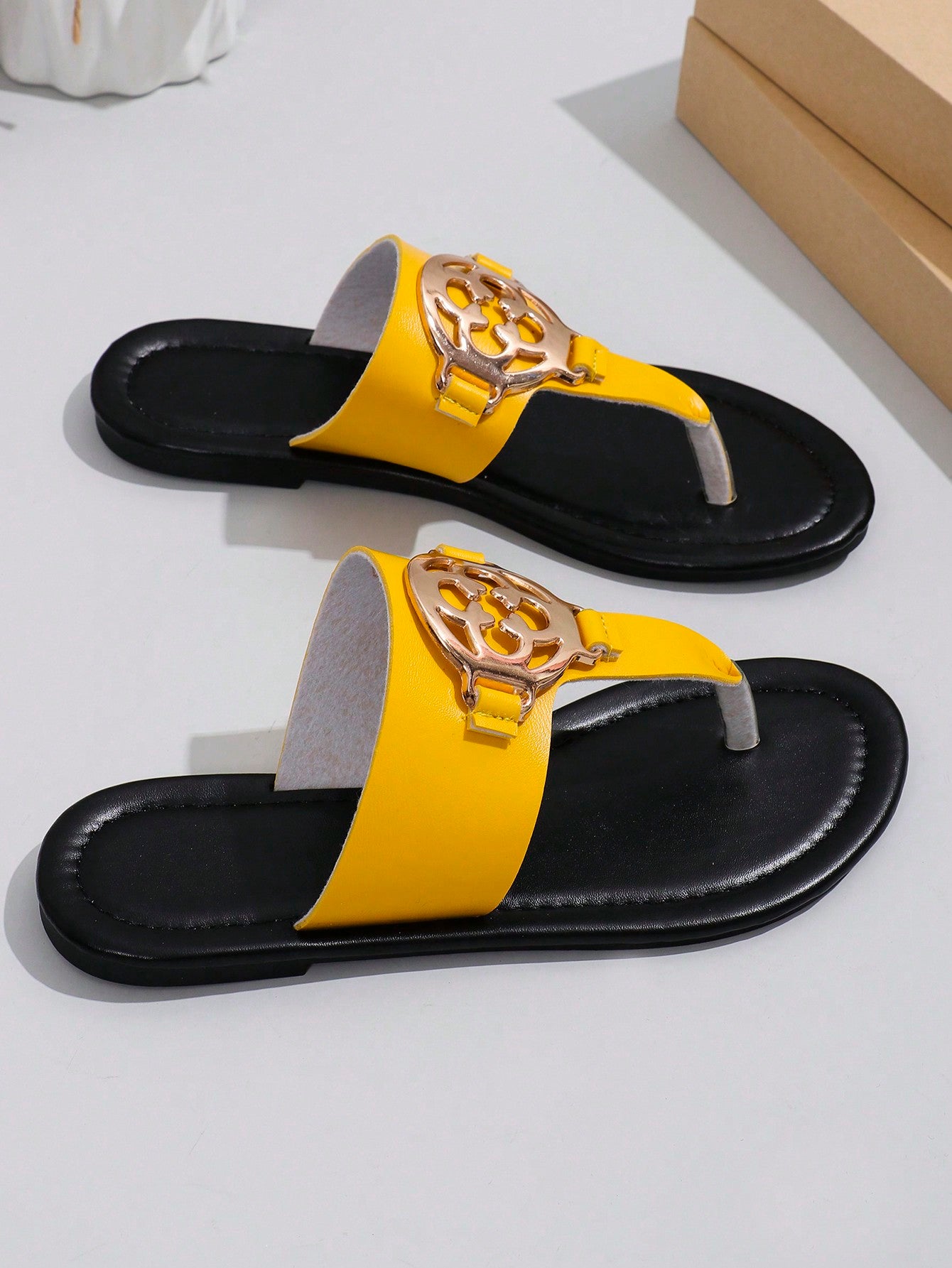 Women's flat slide sandals with toe post strap, cut-out pattern, and metal detail, designed with a lightweight cushioned sole for casual beach and vacation use.