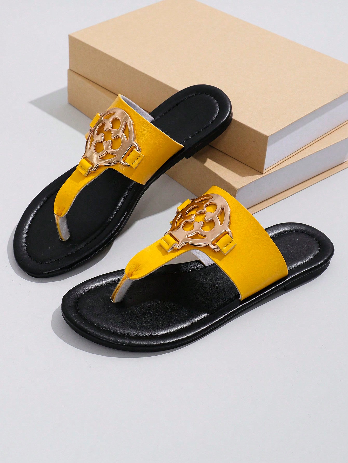 Women's flat slide sandals with toe post strap, cut-out pattern, and metal detail, designed with a lightweight cushioned sole for casual beach and vacation use.
