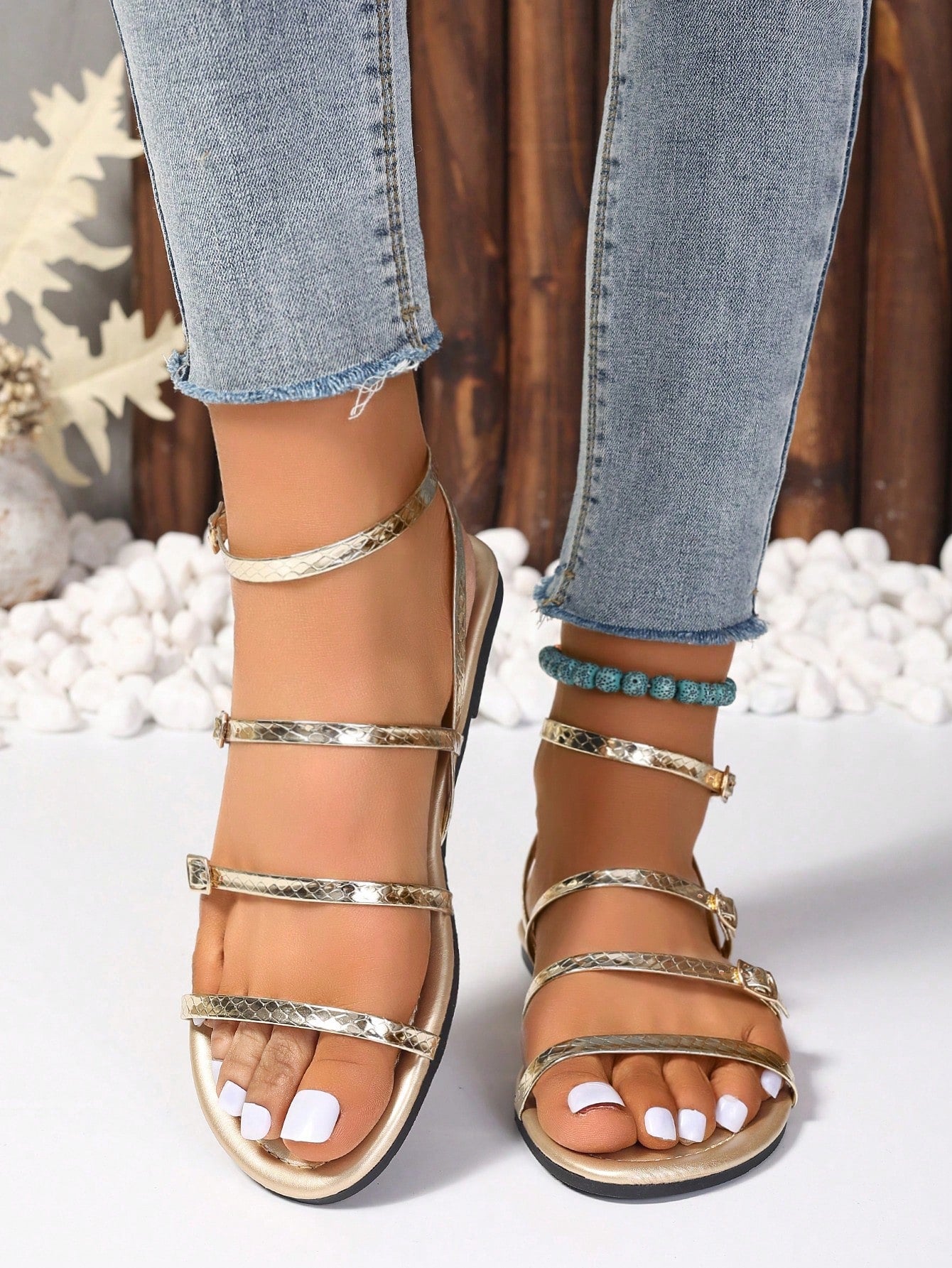 Pair of women's gold flat strappy sandals with buckle closure and open toe design.