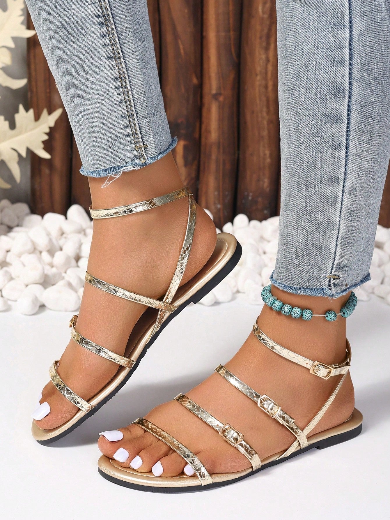 Pair of women's gold flat strappy sandals with buckle closure and open toe design.