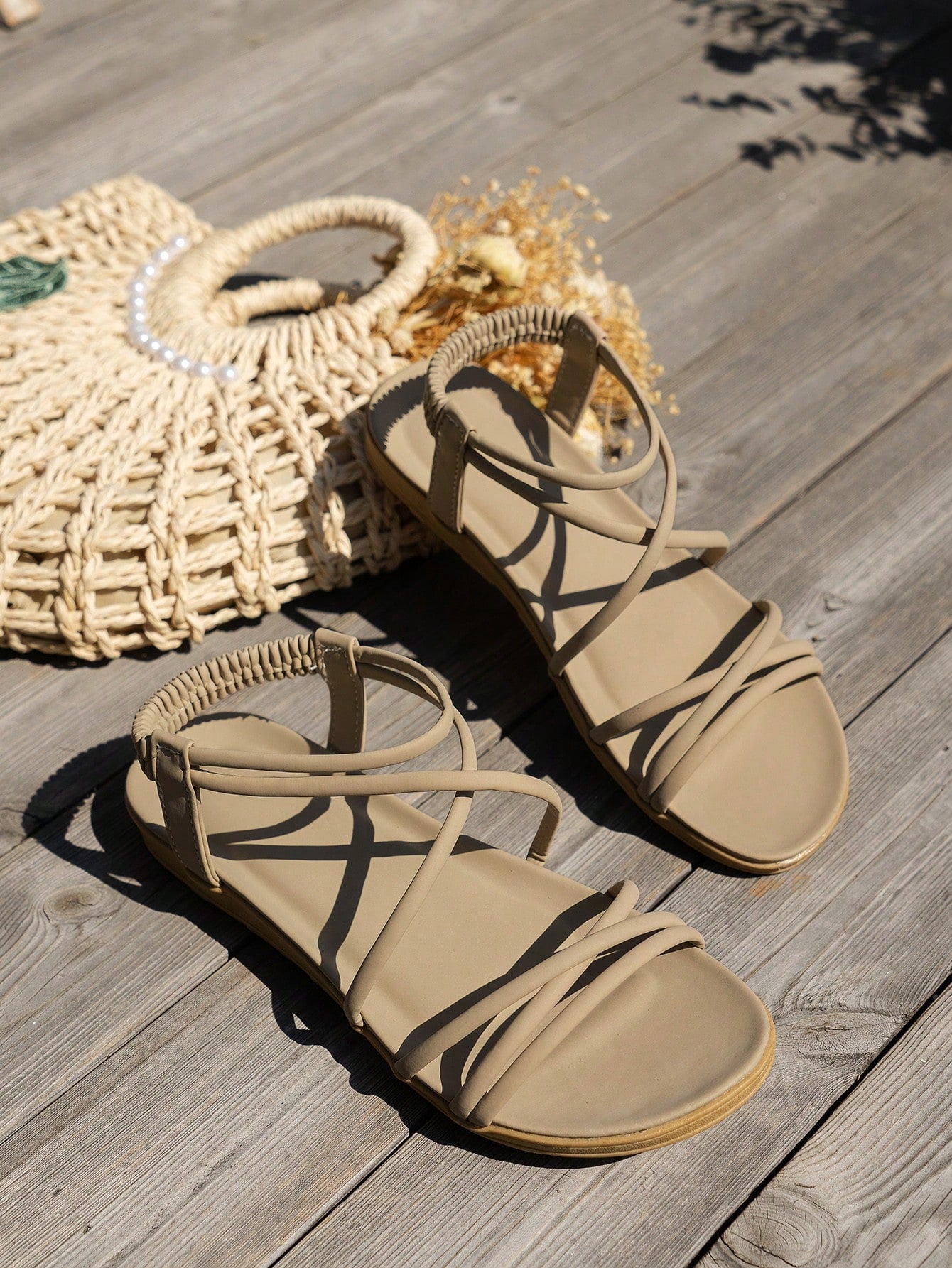 Women's beige flat sandals with criss cross straps, ankle strap, and open toe.
