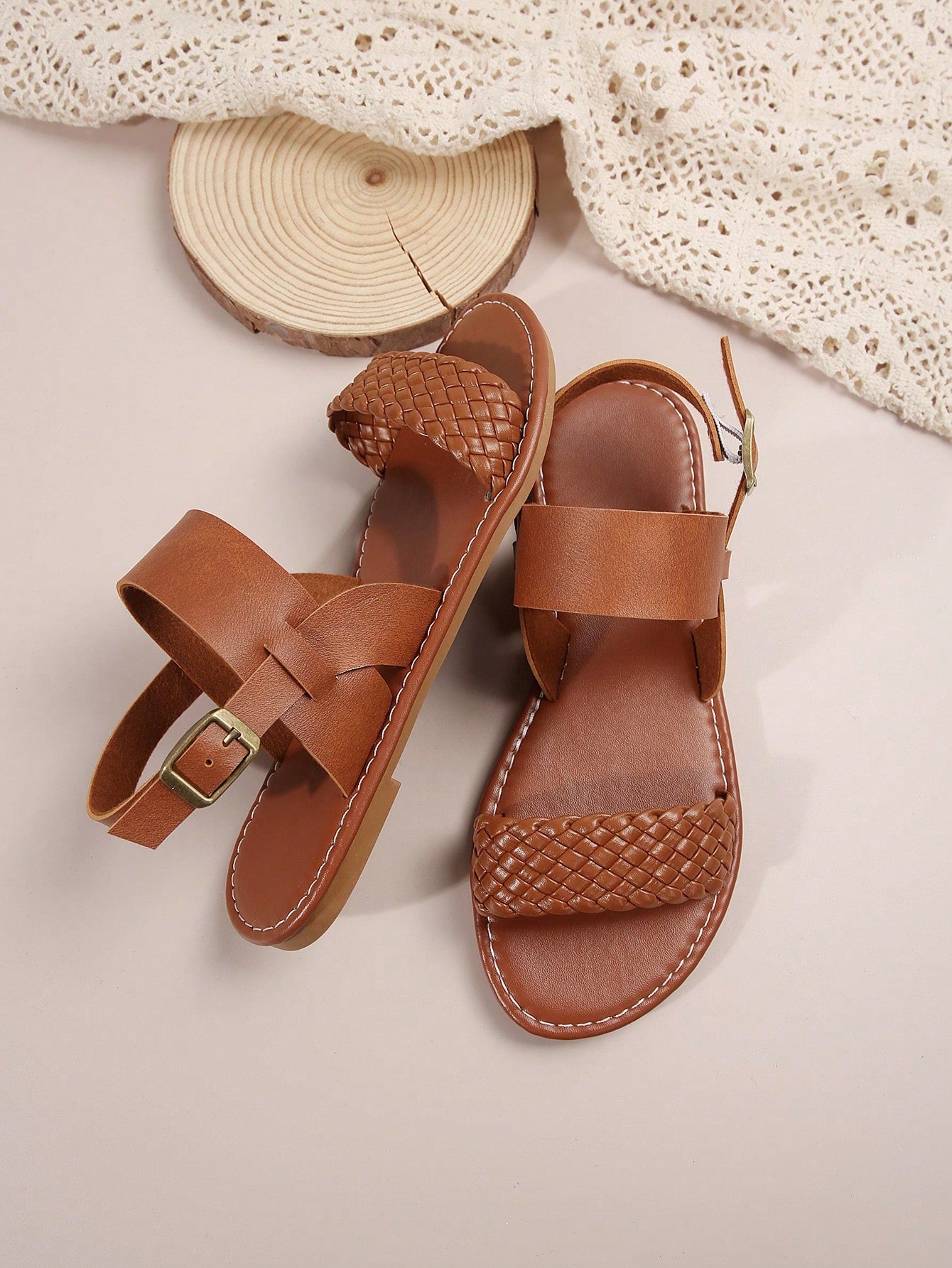 Pair of women’s coffee brown flat sandals with woven braid straps, open toe design, and buckle closure, suitable for casual beach outfits.