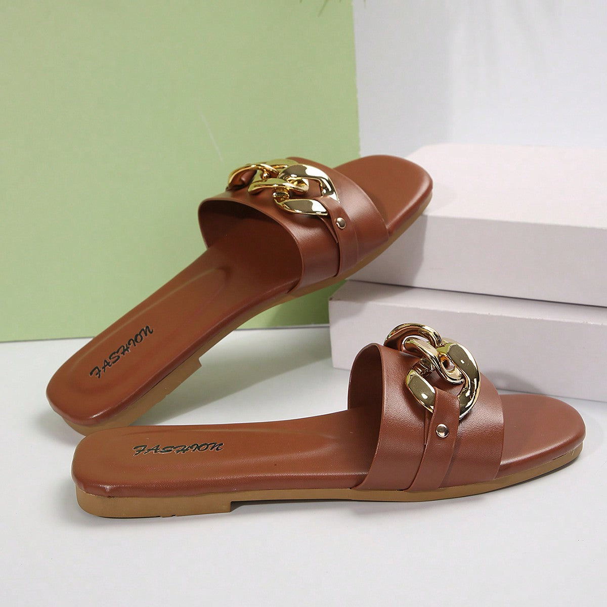 Women's gold-tone slip-on slide sandals with open toe and chain link detailing, shown as casual flat sandals for indoor and outdoor use.
