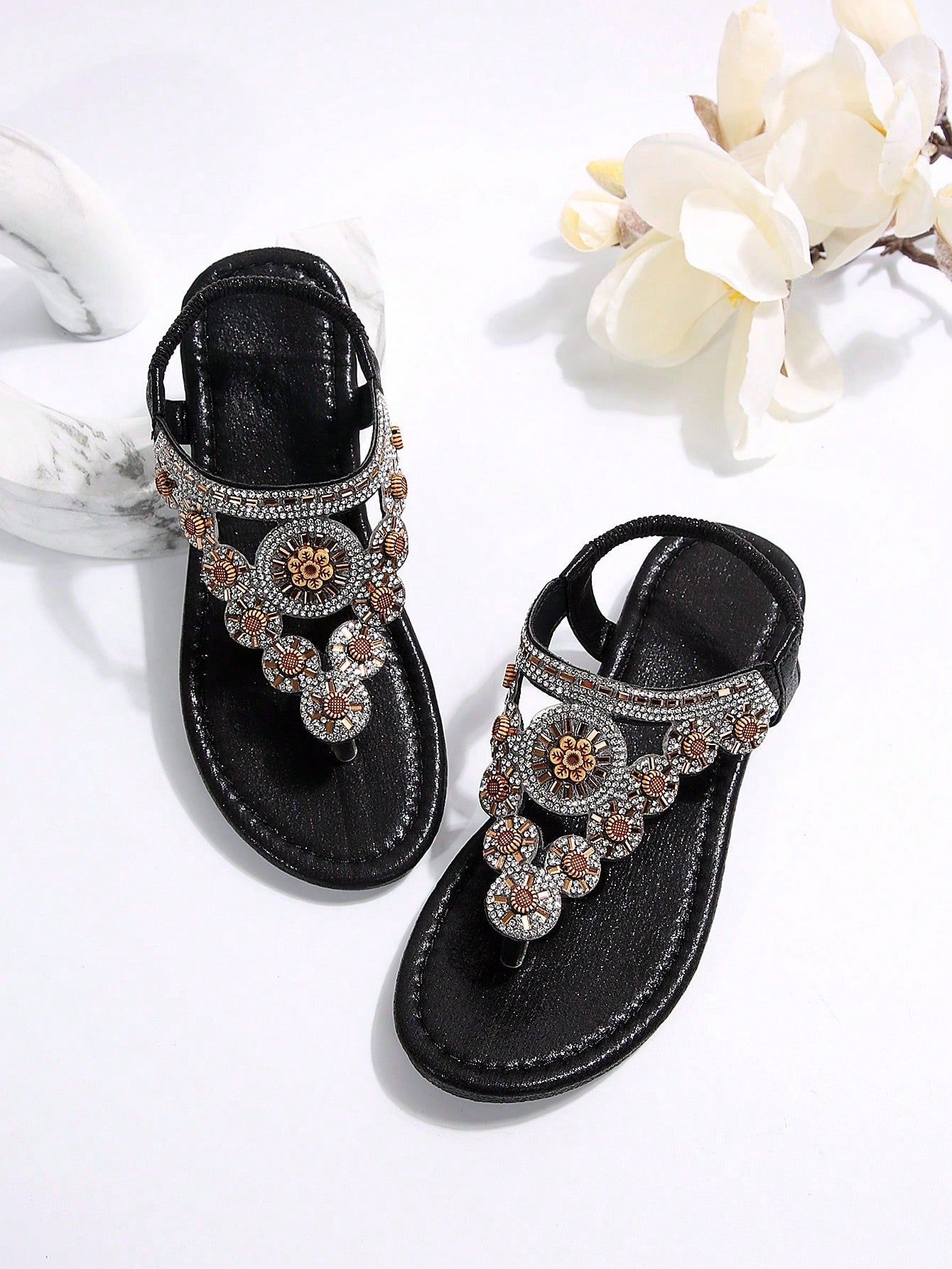 Women's black flat thong sandals with toe post, rhinestone embellishments, and bow detail, designed for beach and summer wear.