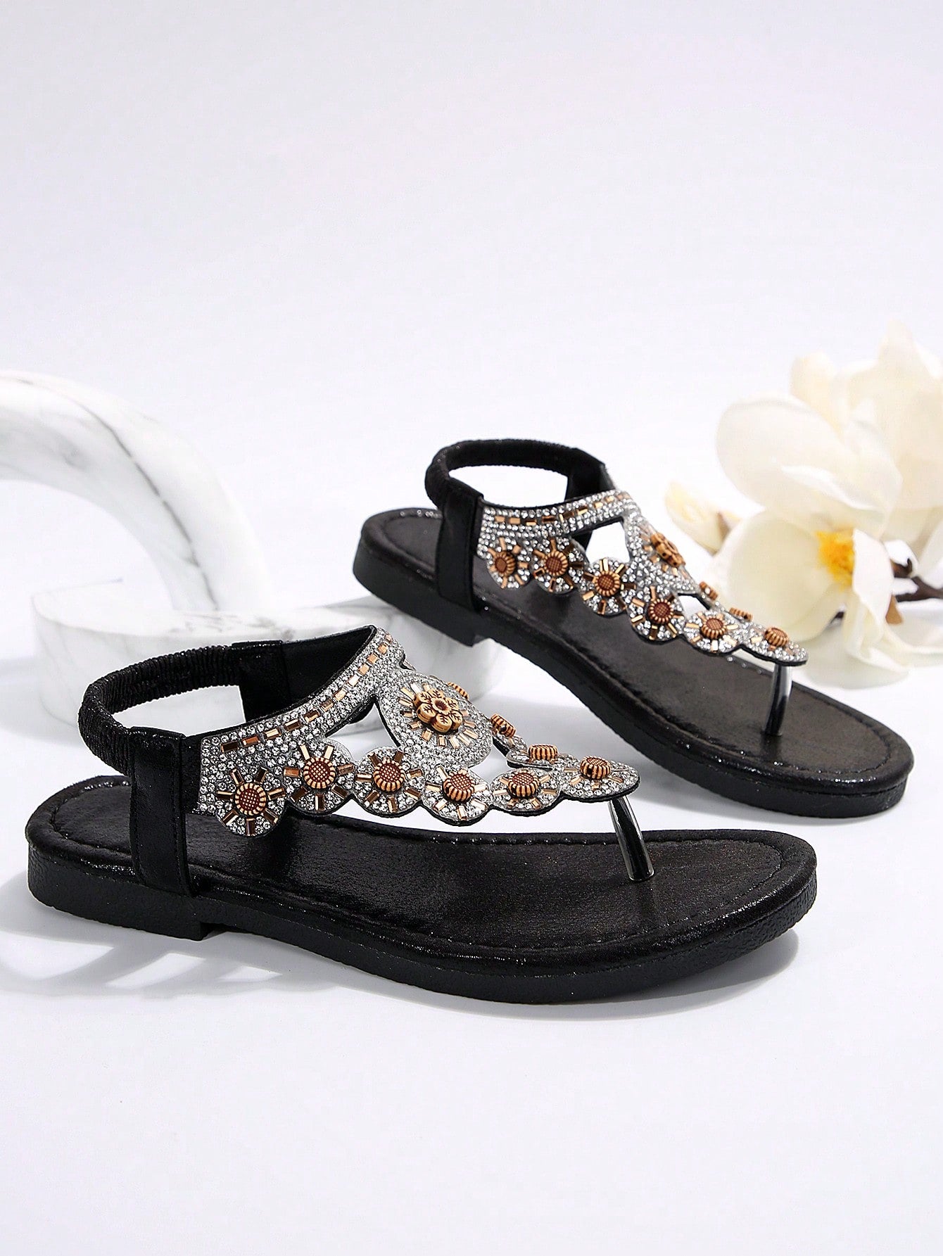 Women's black flat thong sandals with toe post, rhinestone embellishments, and bow detail, designed for beach and summer wear.