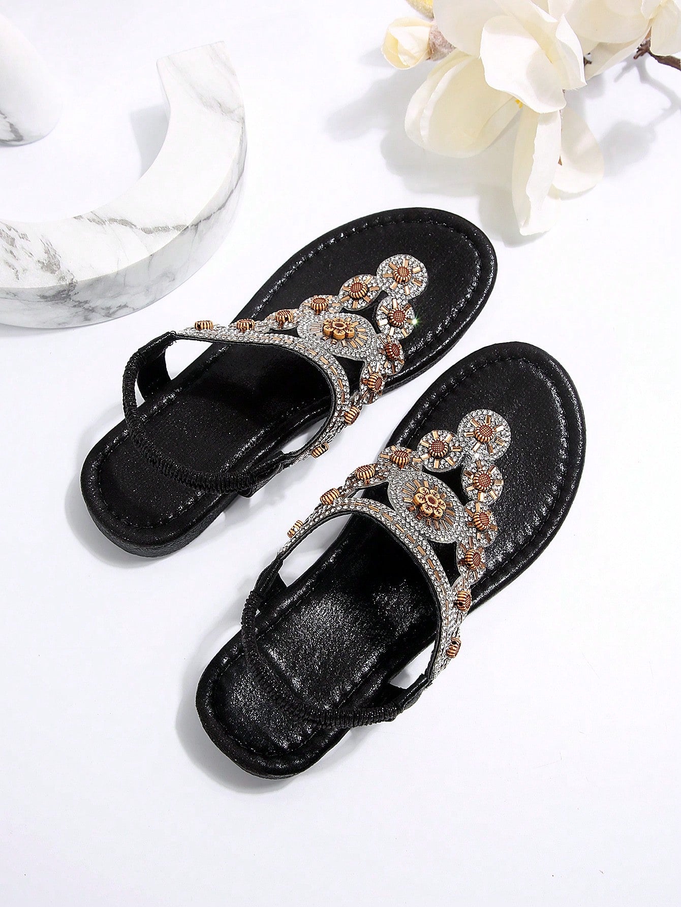 Women's black flat thong sandals with toe post, rhinestone embellishments, and bow detail, designed for beach and summer wear.