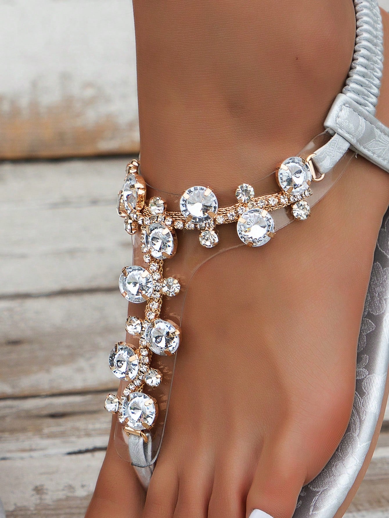 Women's black flat thong sandals with floral print, toe post design, buckle detail, and rhinestone embellishment